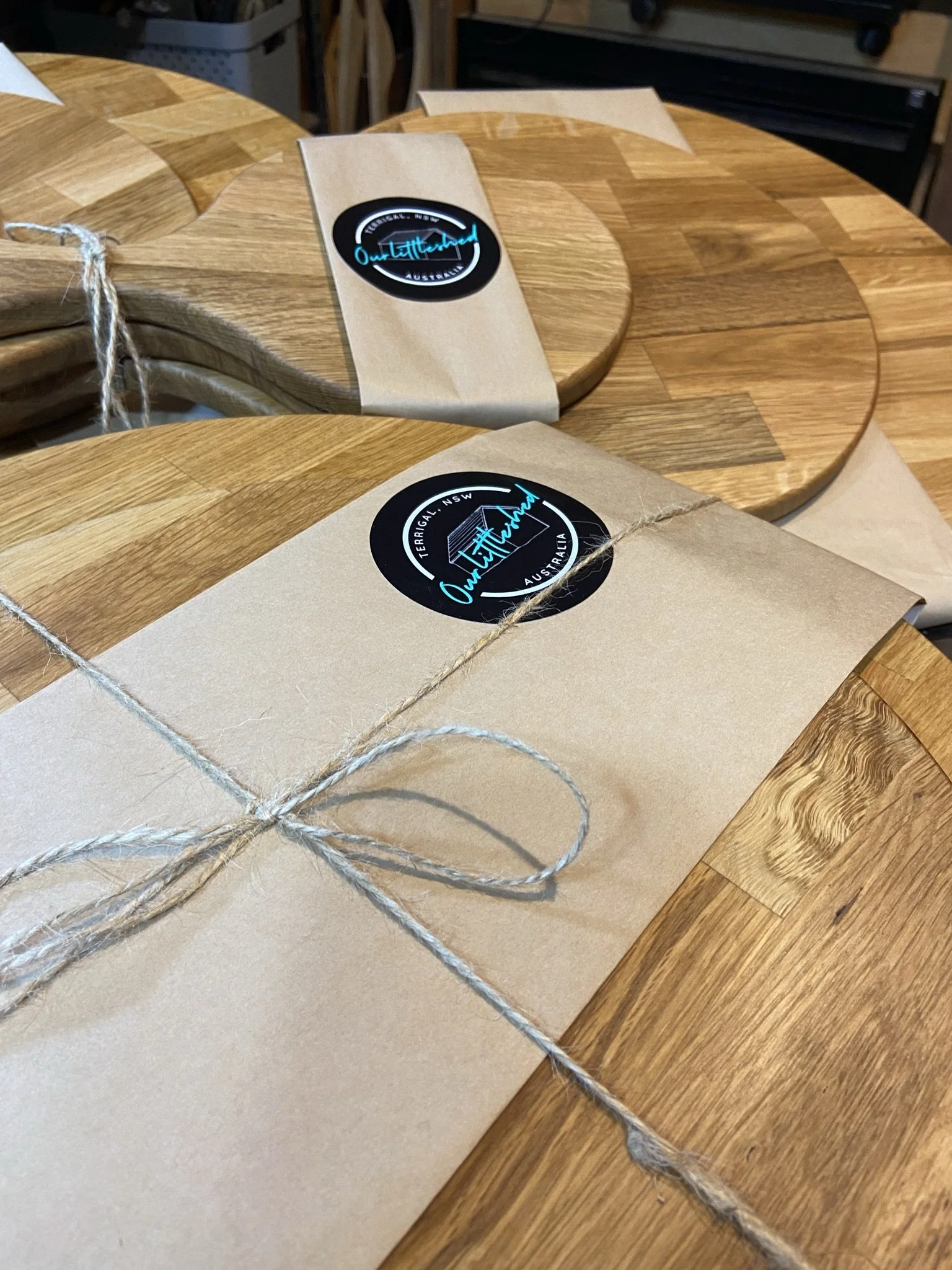 Wooden tables with packages wrapped in brown paper and tied with twine, featuring circular stickers that read "Outland" and "Terrigal NSW Australia."
