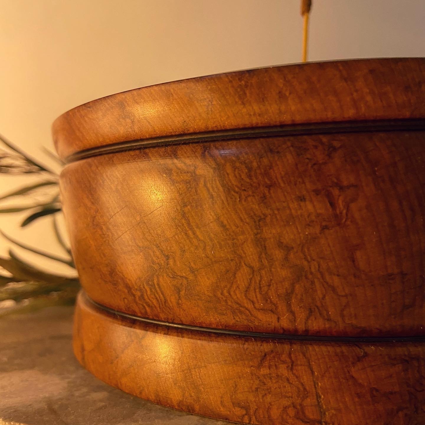 Close-up of a round wooden container with a lid, showing the wood grain and a slight lip around the edge.