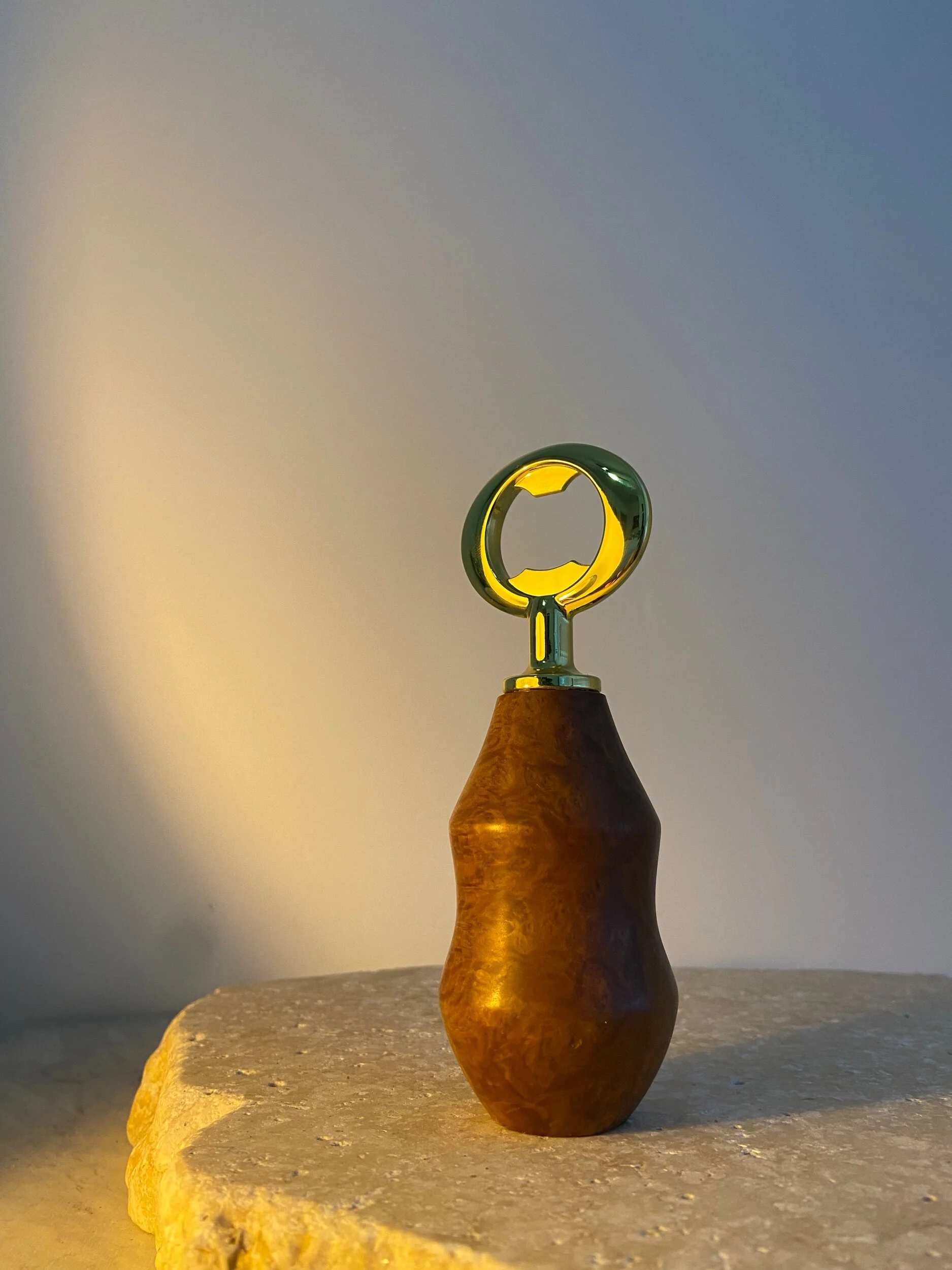 A corkscrew with a wooden handle and a metallic top stands on a textured surface against a gradient background.