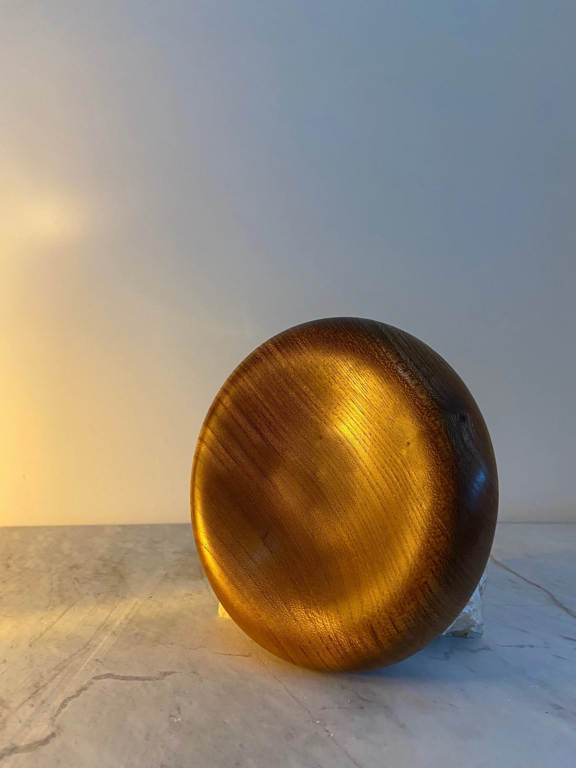 A round, golden-brown, textured object with a smooth surface, positioned on a light-colored surface with a gradient background transitioning from cream to light blue.