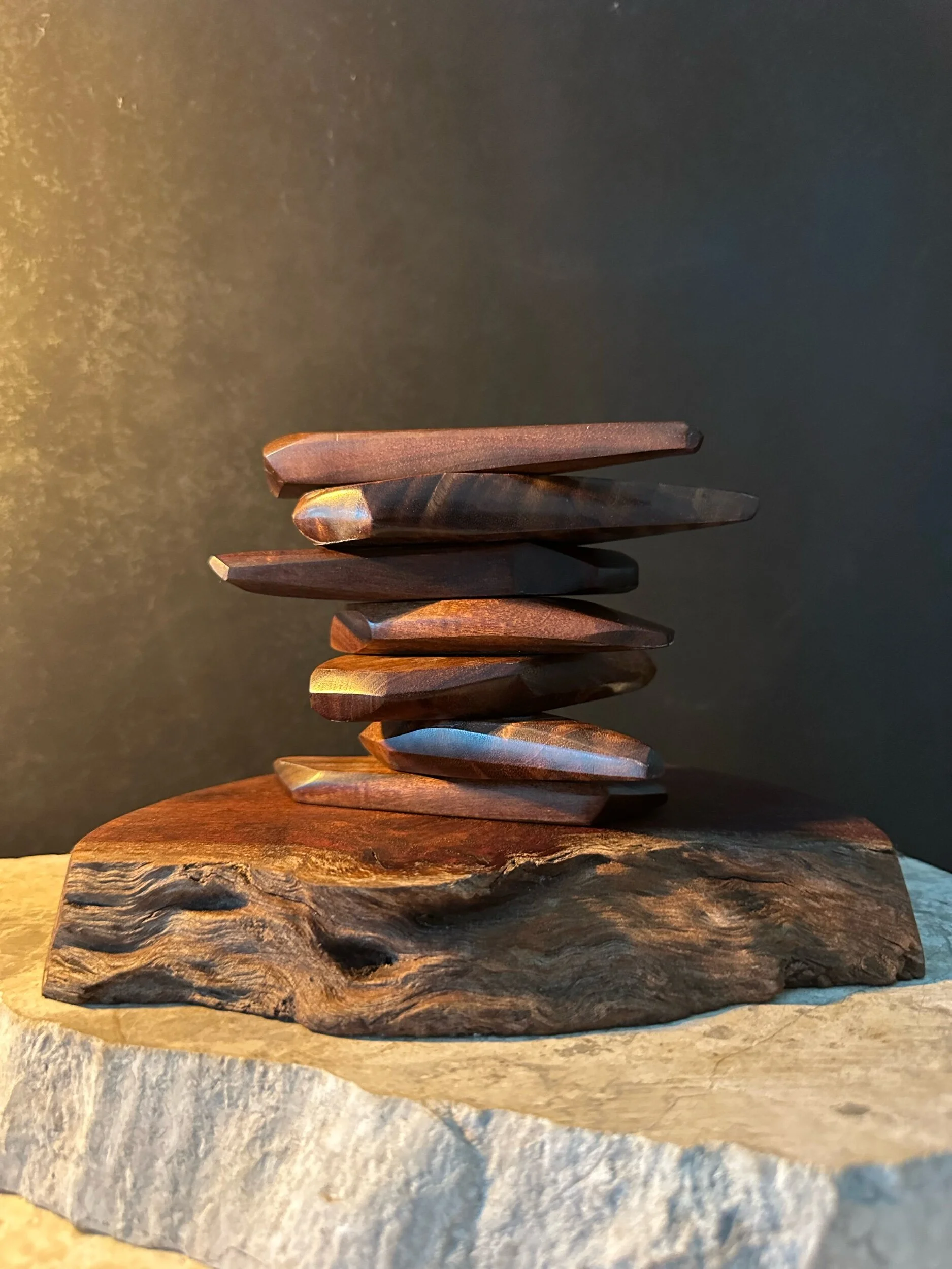Stacked unevenly wooden stones on a rustic wood slab.