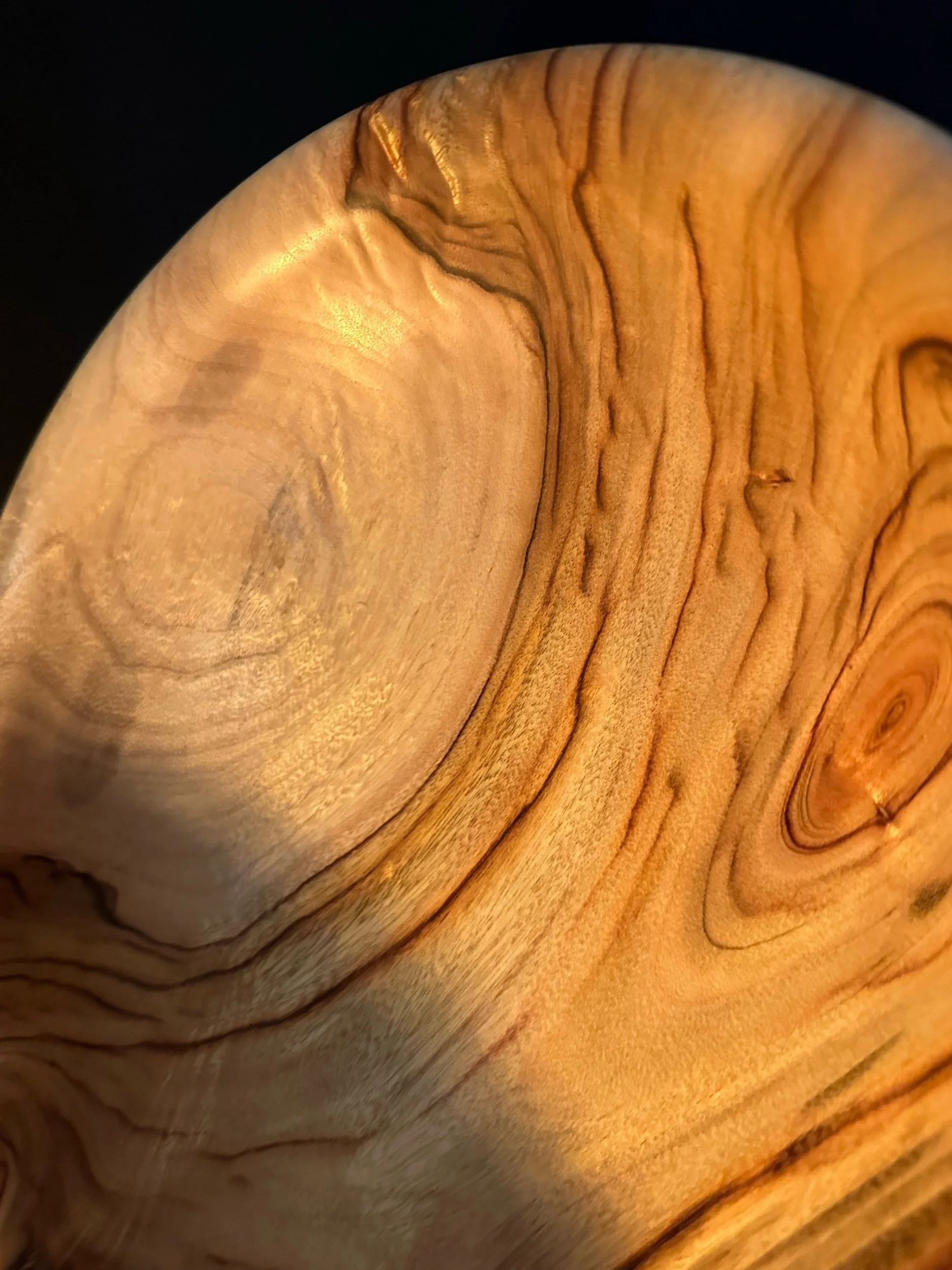 Close-up image of a polished piece of wood with visible grain patterns and a smooth surface.