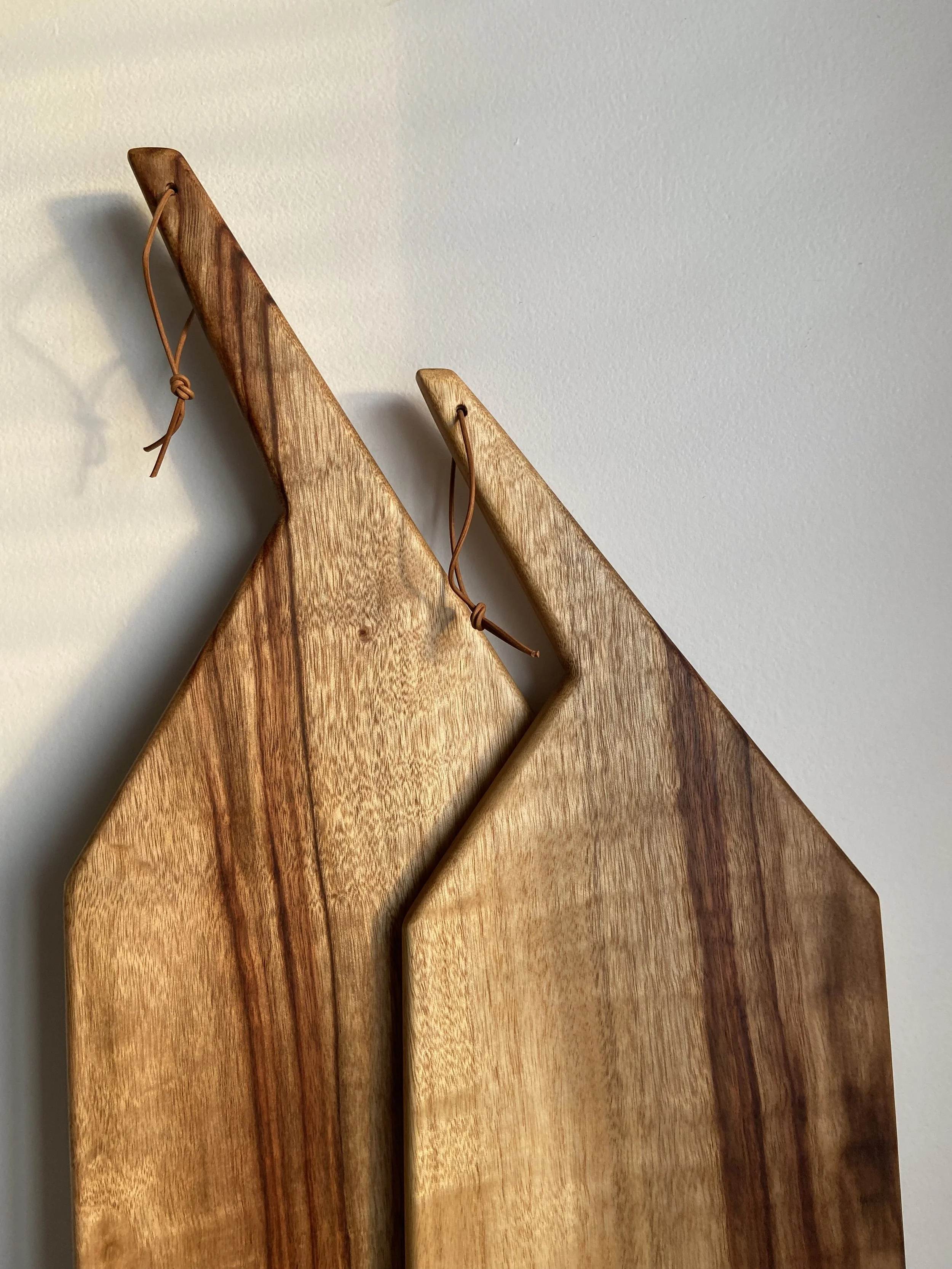 Two wooden snowshoes hanging on a plain white wall.