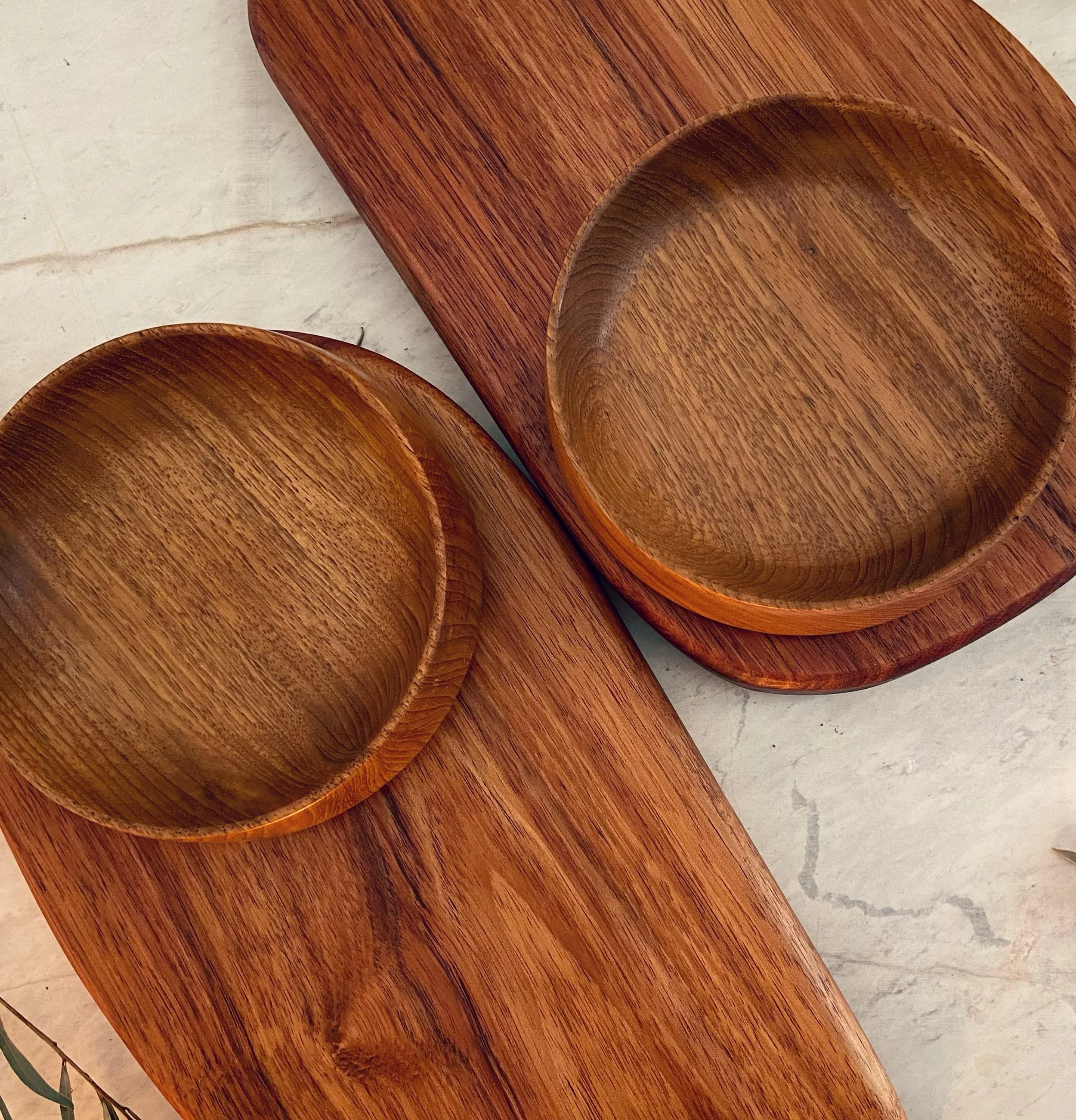 Two wooden bowls on matching wooden trays, placed on a light-colored surface.