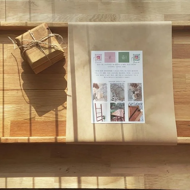 A sealed bundle of kraft paper wrapped around a small stack of paper with a string, resting on a wooden surface, next to a large sheet of brown paper with a flyer attached.