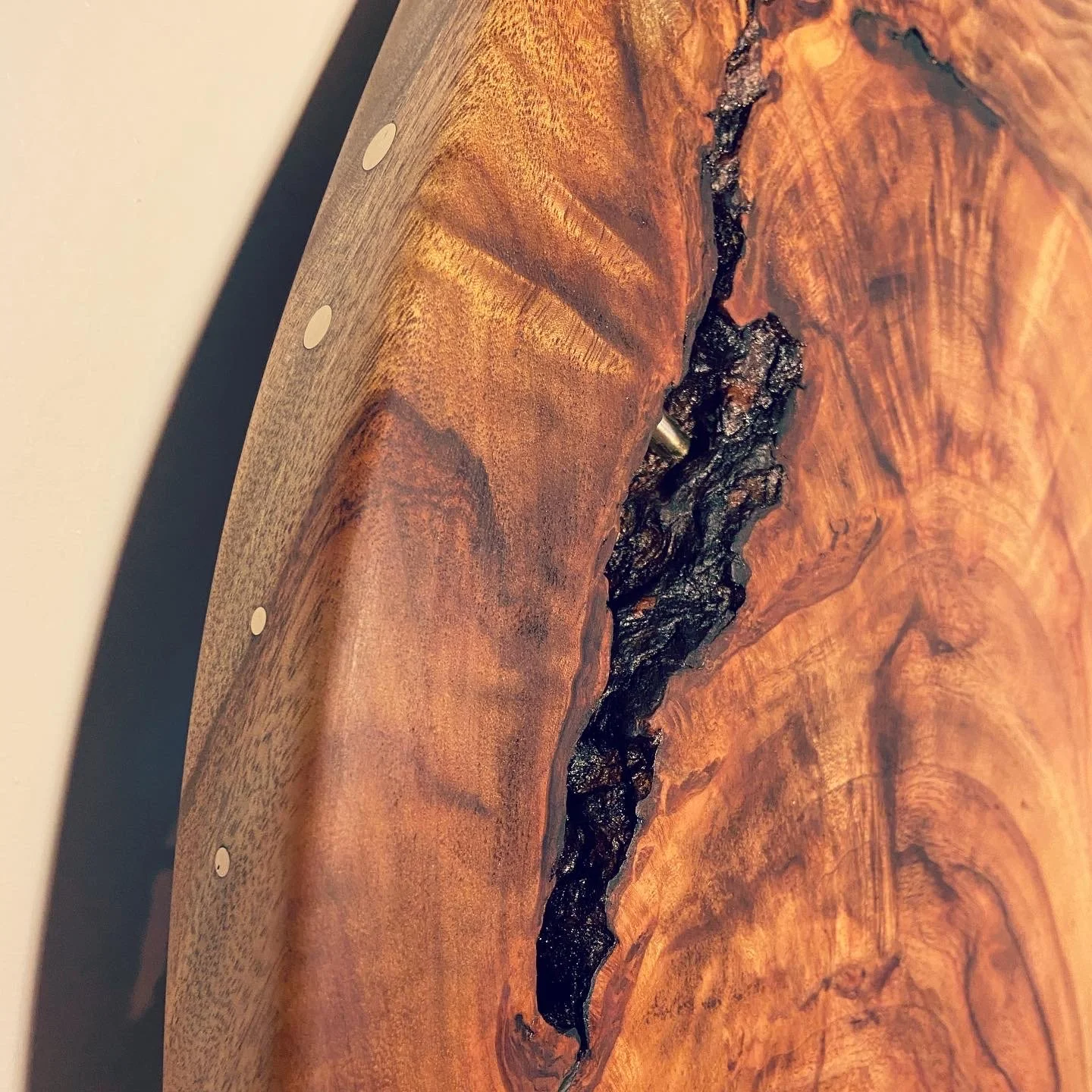 Close-up of a wooden object, possibly a piece of furniture, with a dark, textured crack running through the wood surface.