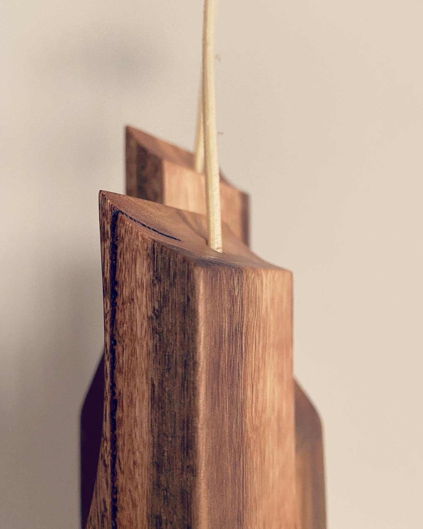 Close-up of a wooden object with a thin stick attached, against a plain white background.
