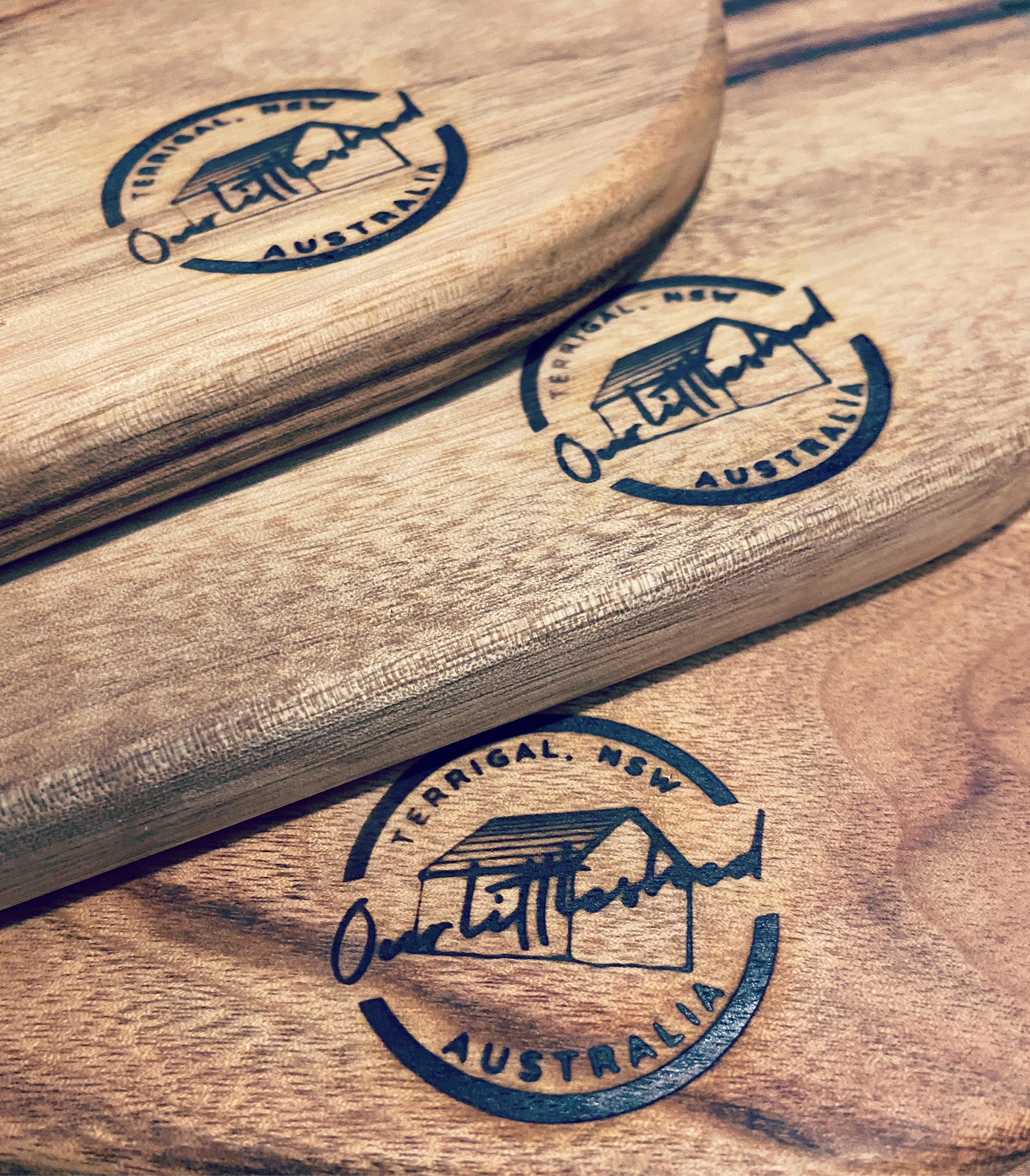 Close-up of wooden boards with a circular logo that reads 'Teriginal, NSW, Australia' with a drawing of a shed, some of the logo is stamped on different boards.