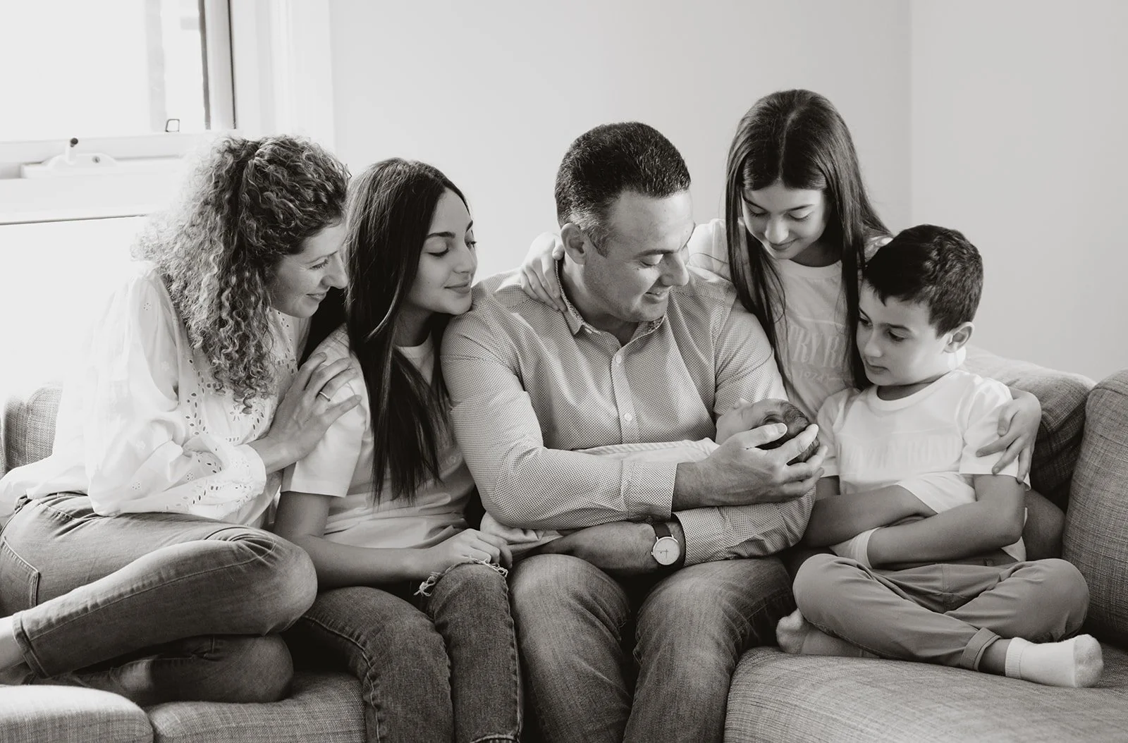 Family sitting together on a couch during an indoor portrait session, photographed by Shadowfax Photography in Melbourne.