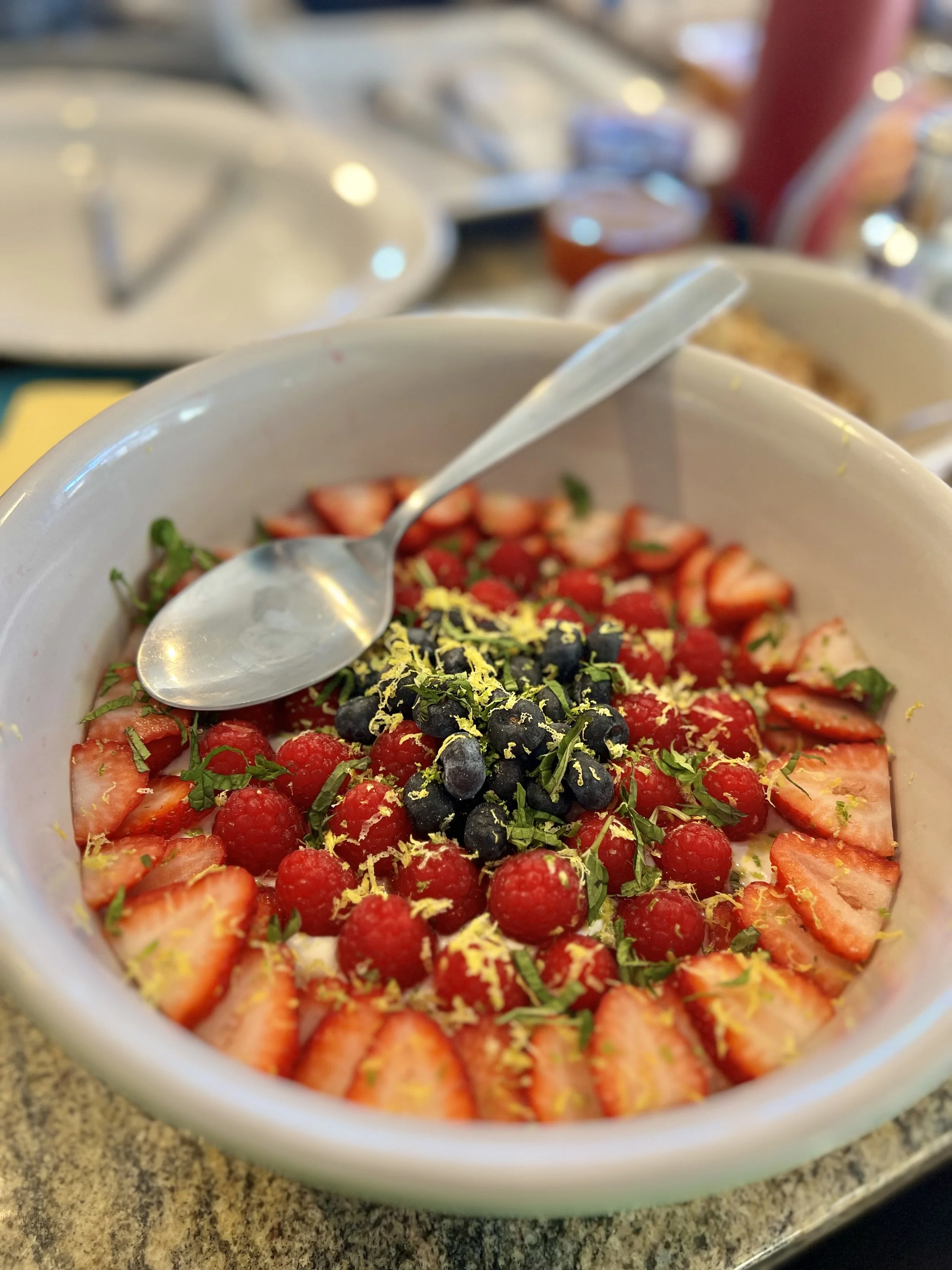 A bowl of fresh strawberry and mixed berry fruit salad with lemon zest and herbs.