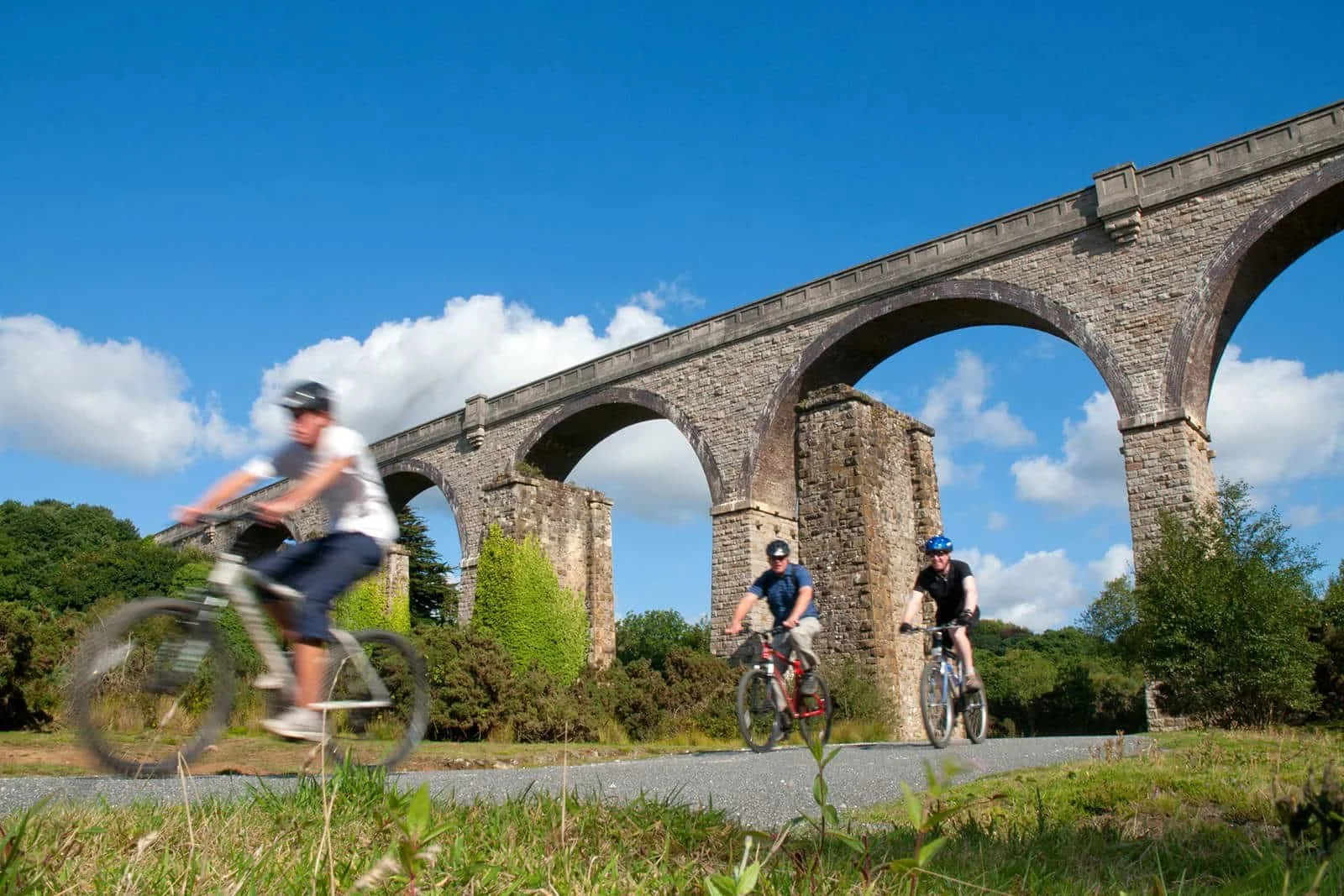Cyclists riding under a railway arch on the Bissoe Trail, Cornwall