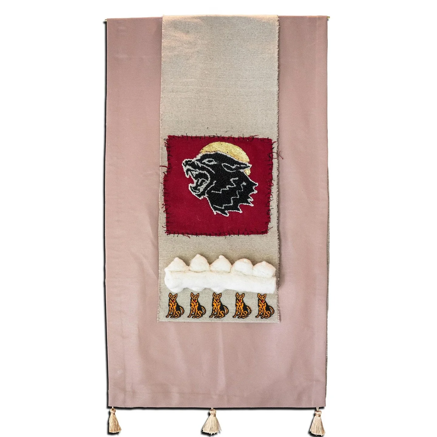 &bdquo;Wolfmother&ldquo;. 
Textile, wool, oil stick, gold leaf. 
50x100 cm, 2024. 

A pink leather ground carries a stitched wolf, felted teats, and a row of identical German Shepherd badges.
The work traces the rise and eventual fragility of patriar
