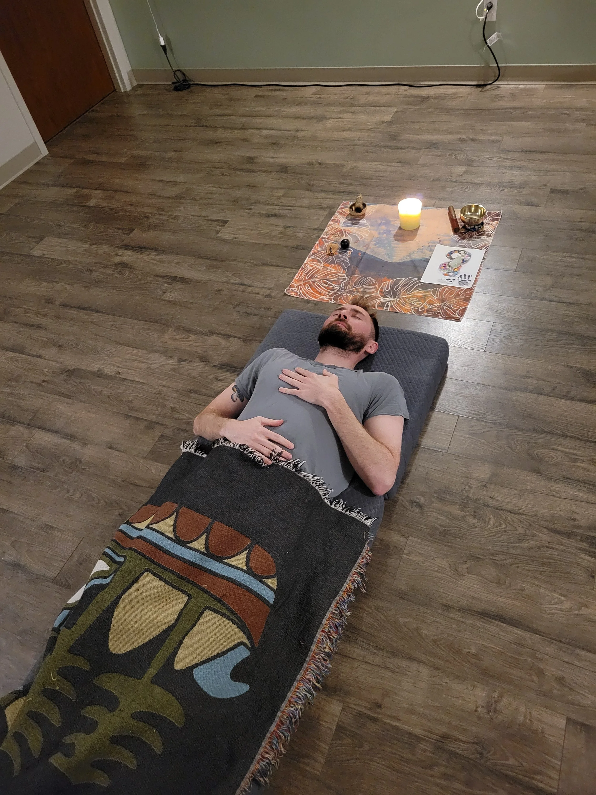 Image of man laying on yoga mat with candle and blanket