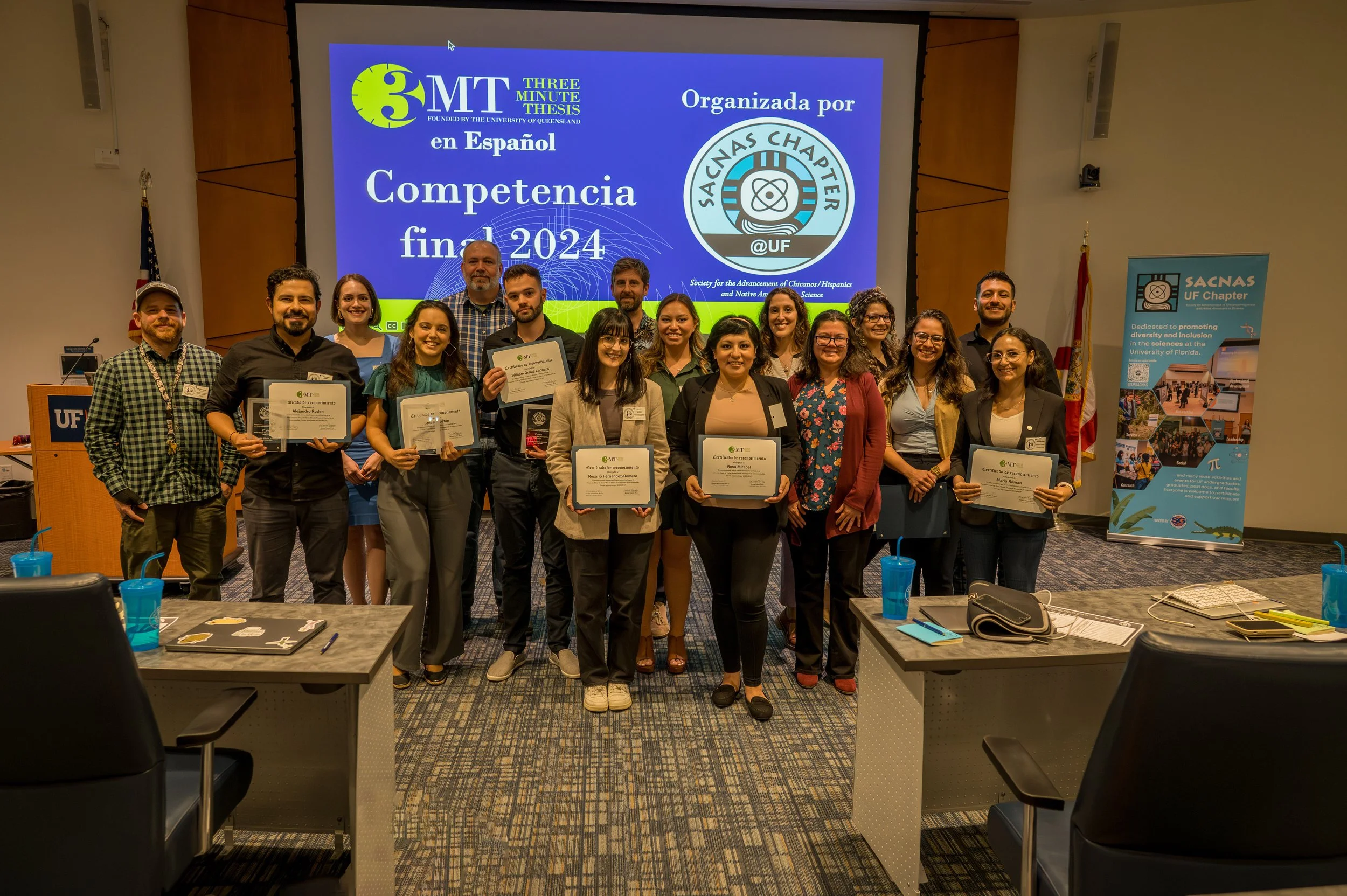 Group of people standing in front of a sign with the 3MT en Espanol and SACNAS logos