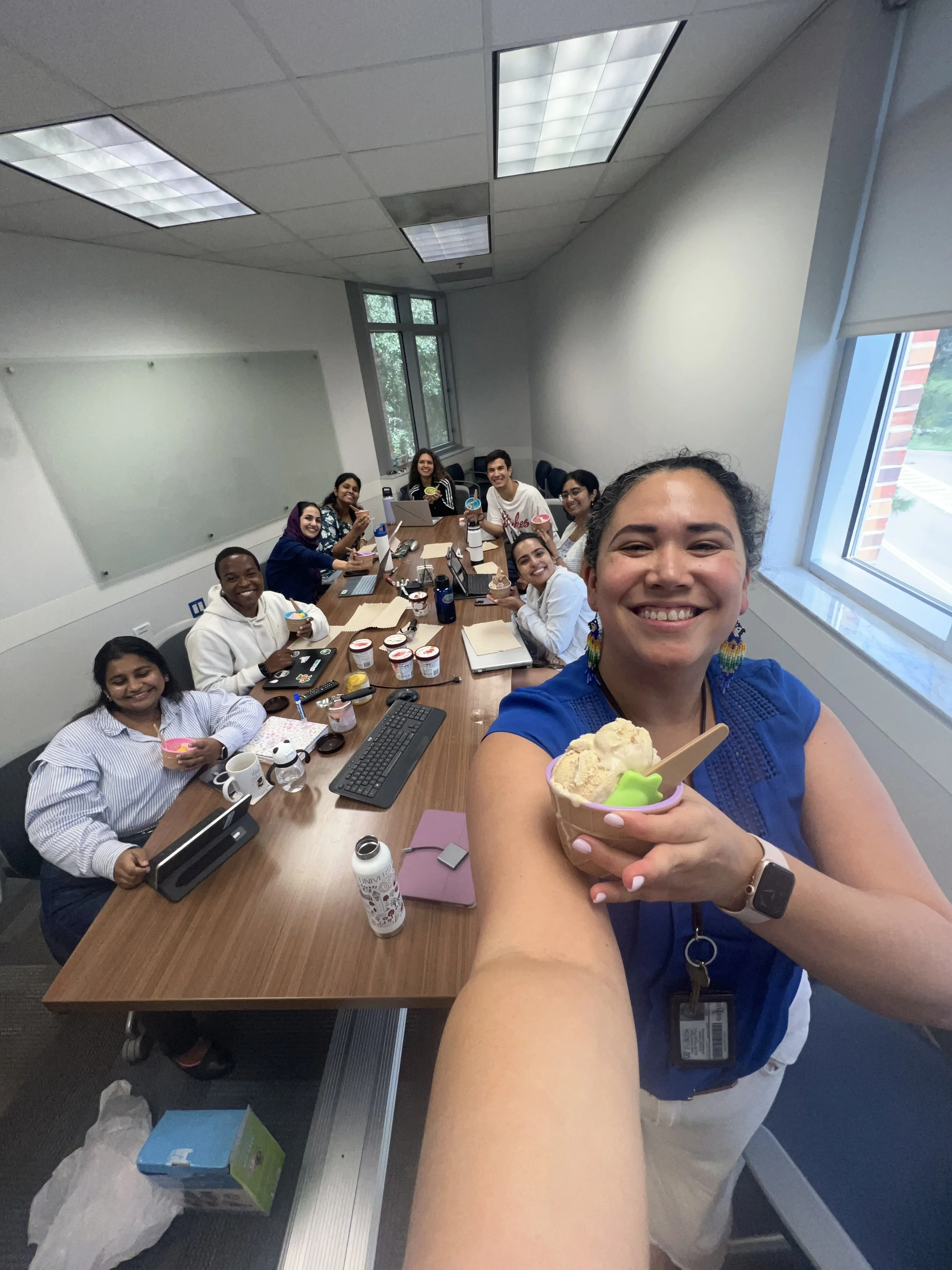 Team ice cream break during a meeting, captured in a group selfie around the conference table.