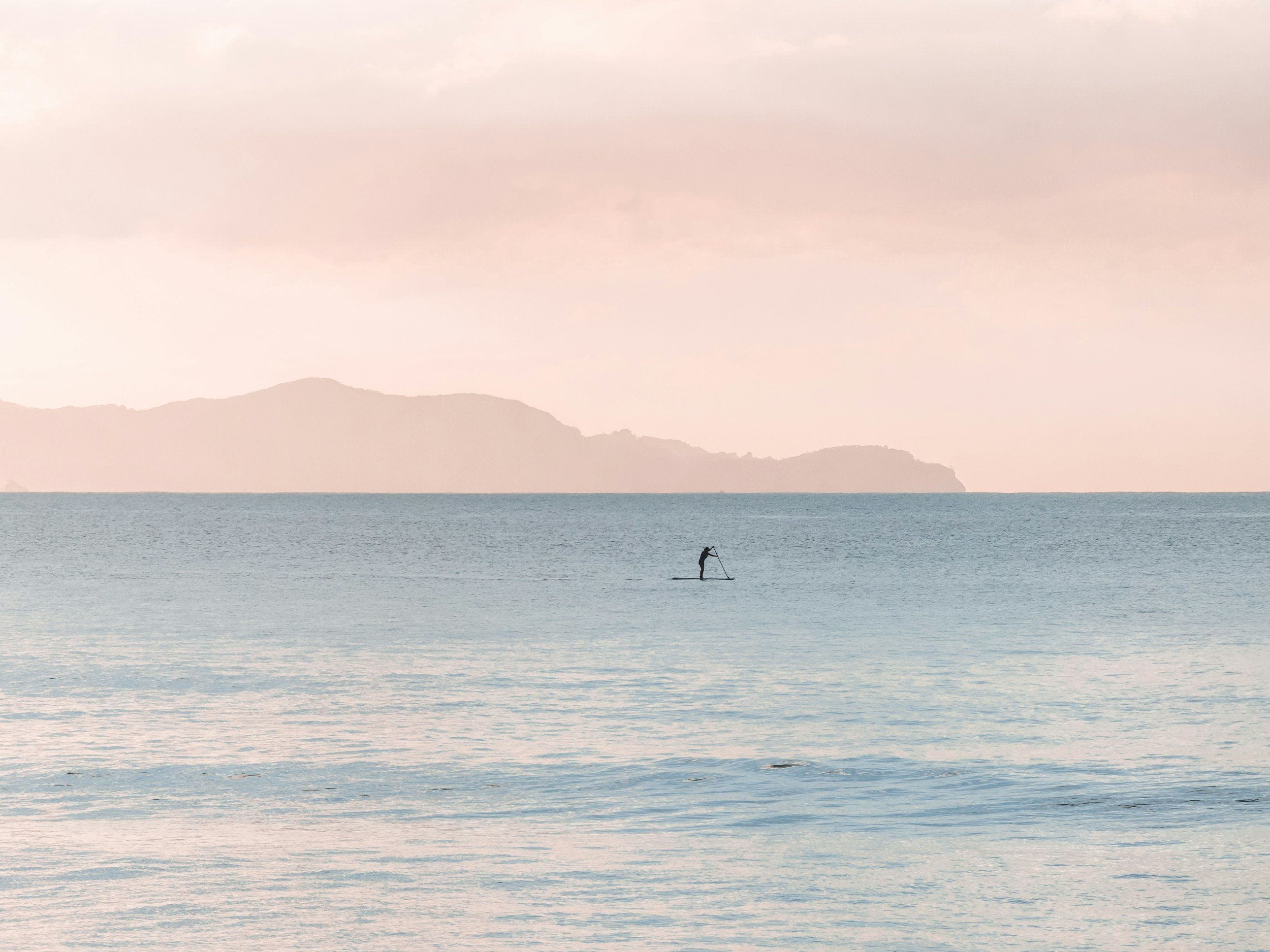 Calm water lake with paddle board and hills in backgroung