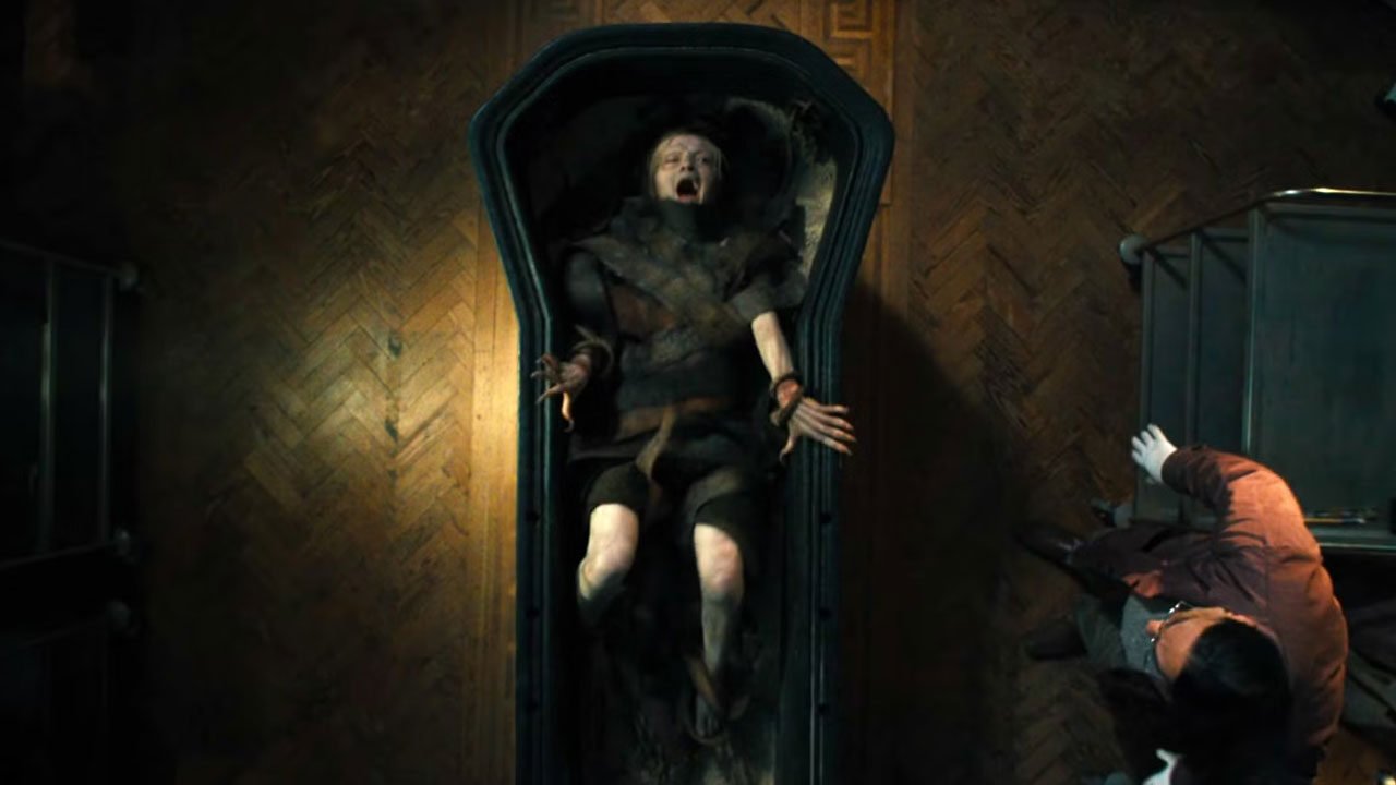 A girl wrapped in scraps screams from within a sarcophagus