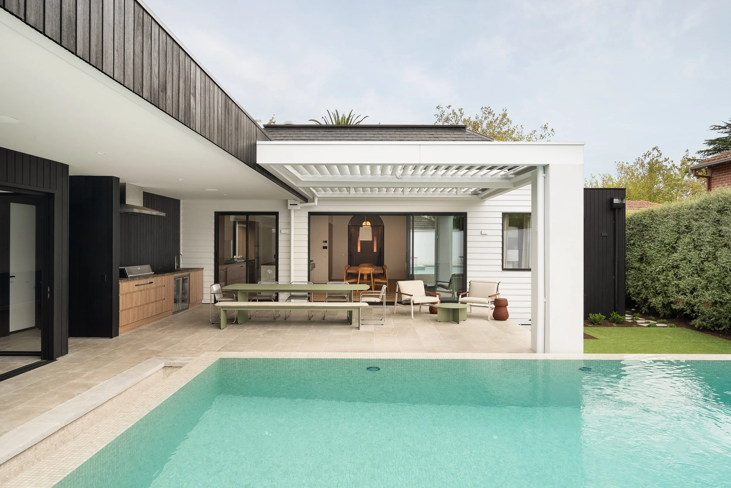 Modern backyard with swimming pool, outdoor dining area, and patio seating.