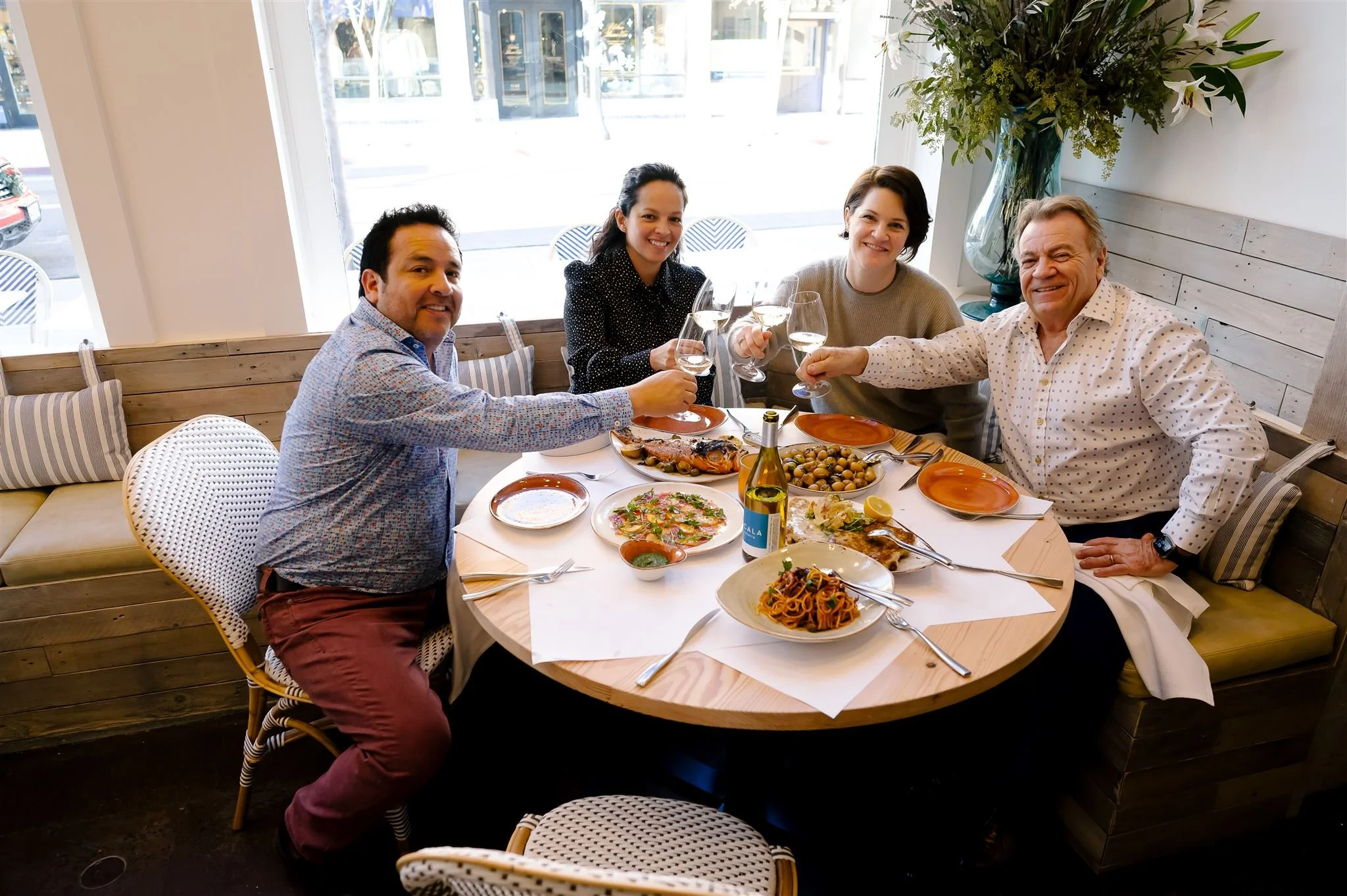 The Scala and Diaz families dining together at Scala Osteria in Napa Valley, sharing Italian seafood, pasta, and wine at a round table in a warm, welcoming dining room.
