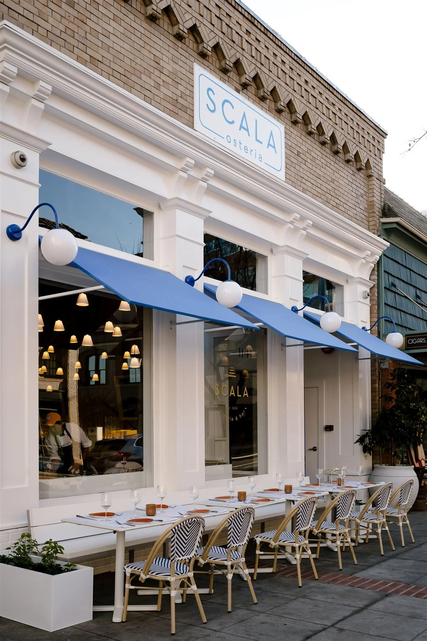 Exterior of Scala Osteria in Napa Valley with blue awnings and sidewalk patio seating along First Street, inviting you to come inside