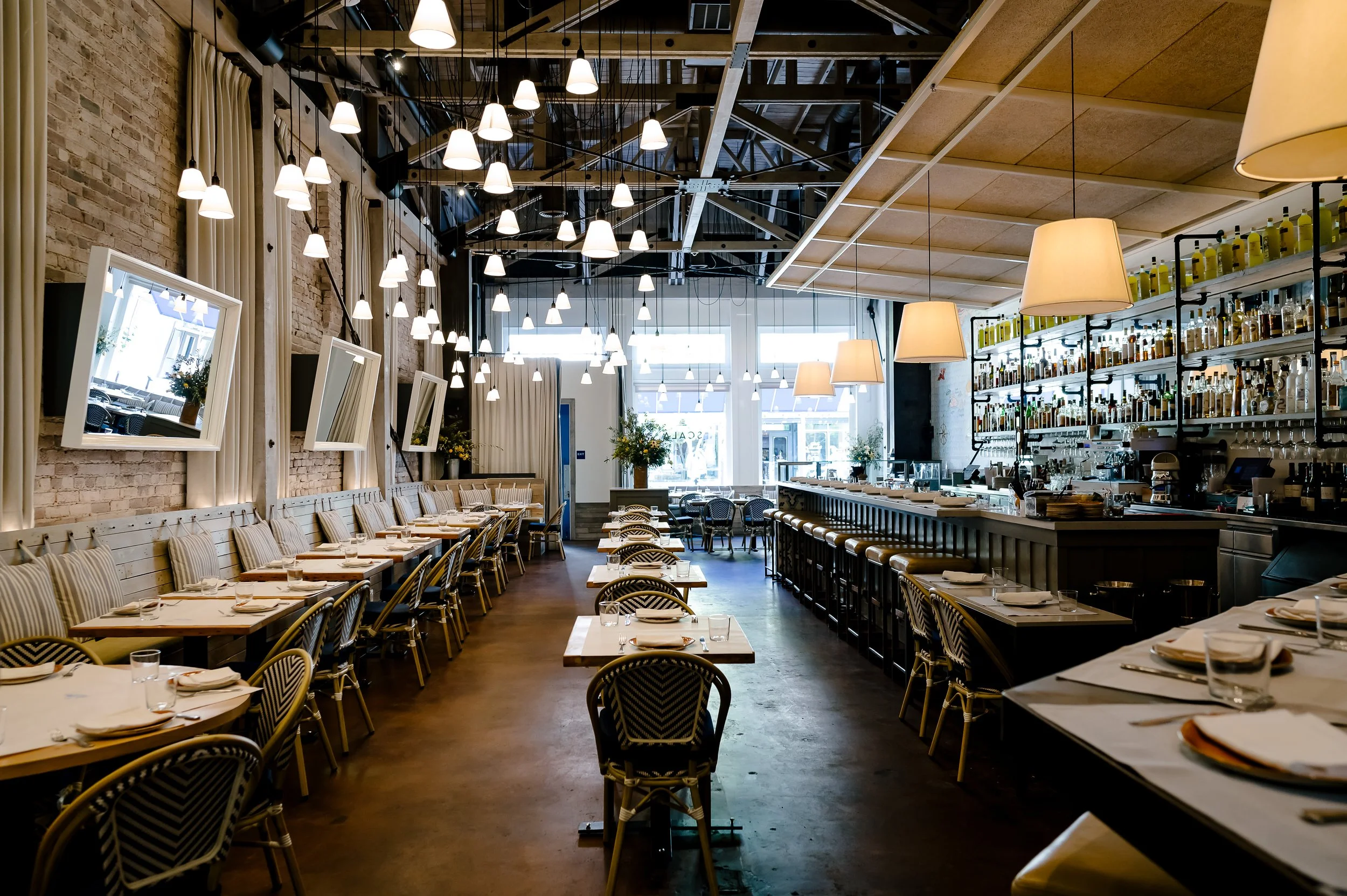 Main dining room at Scala Osteria in Napa Valley with bar seating, dining tables, and modern pendant lighting, featuring an open, airy restaurant interior ideal for lunch and dinner service.