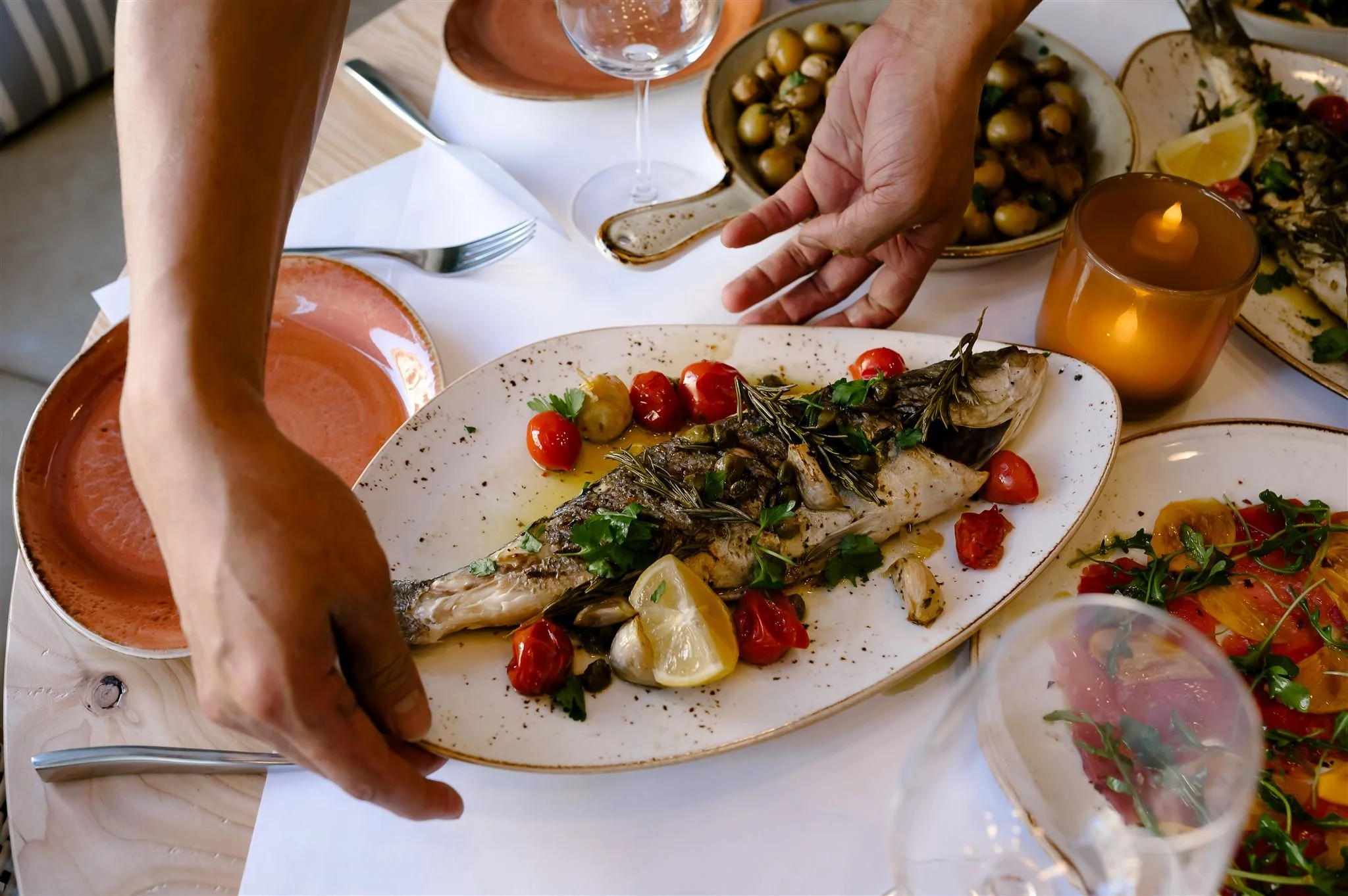 Whole roasted fish served at Scala Osteria in Napa Valley with cherry tomatoes, lemon, herbs, and olive oil, plated tableside as part of an Italian seafood dining experience.
