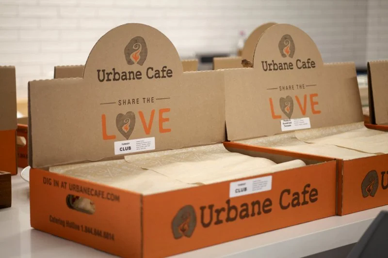 Empty cardboard display boxes for Urbain Cafe with the message "Share the LOVE" and the cafe's logo.