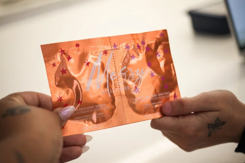 Close-up of hands holding a shiny, orange-colored booklet or card with purple and red star decorations, on a white surface.