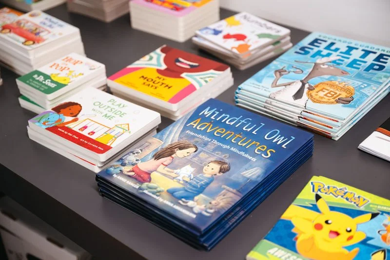 Stacks of children's books about mindfulness, outdoor play, and adventures displayed on a table.