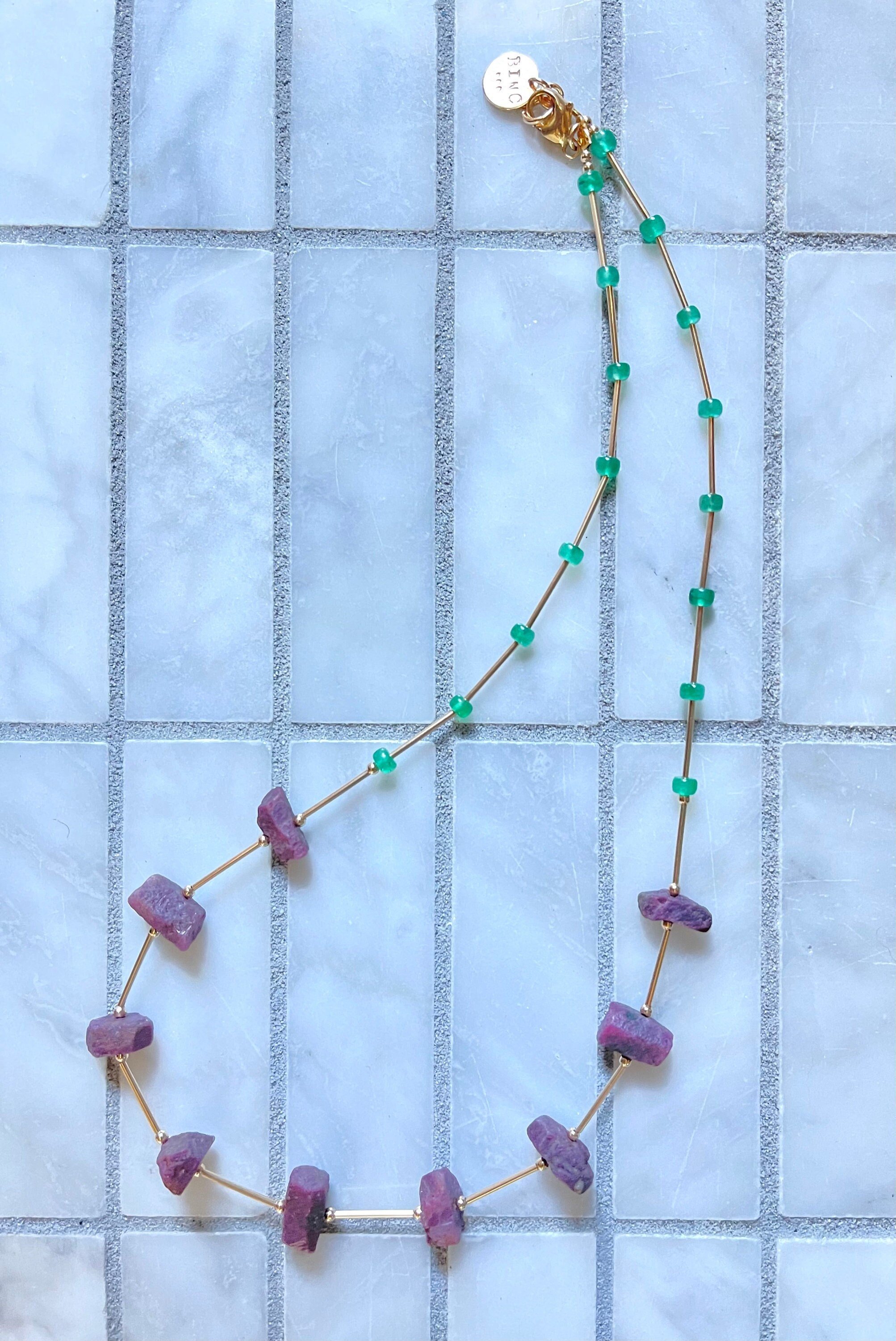 CHRYSSA Ruby Emerald Necklace Hanging On Display