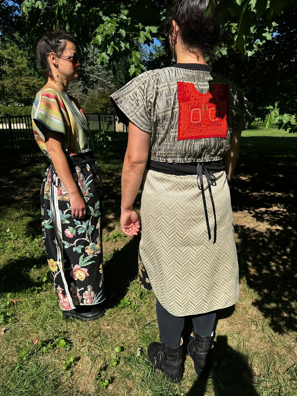 Frida Capelet with hand-embroidered antique tribal panel worn reversed on the back and Piper skirts/capes/dresses on models standing facing each other