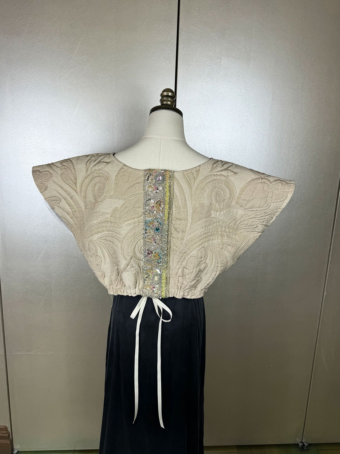 Frida Capelet with antique Sari fragment panels worn reversed on back on mannequin close up with gros grain ribbon bow tie
