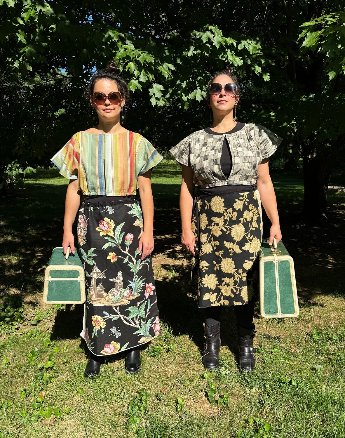 Frida Capelets worn reversed and Piper skirts/dresses/capes on models standing with suitcases