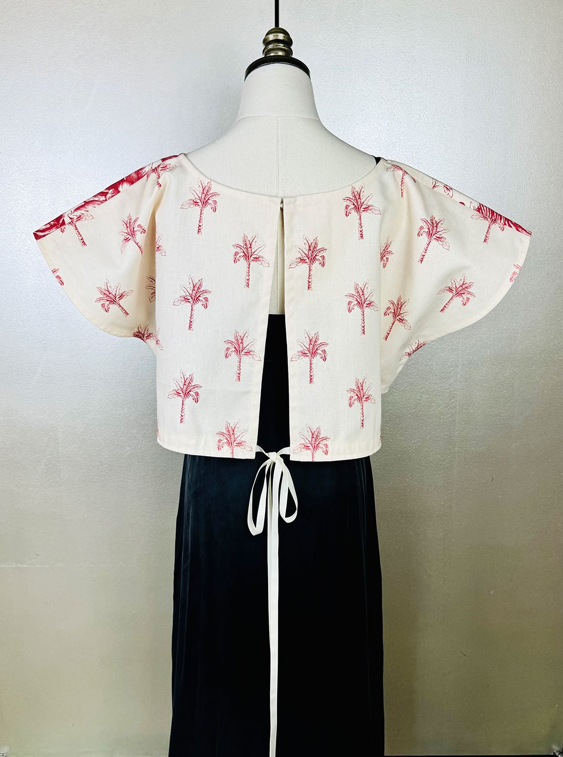 Frida Capelet shown on back and worn with ribbon bow on mannequin