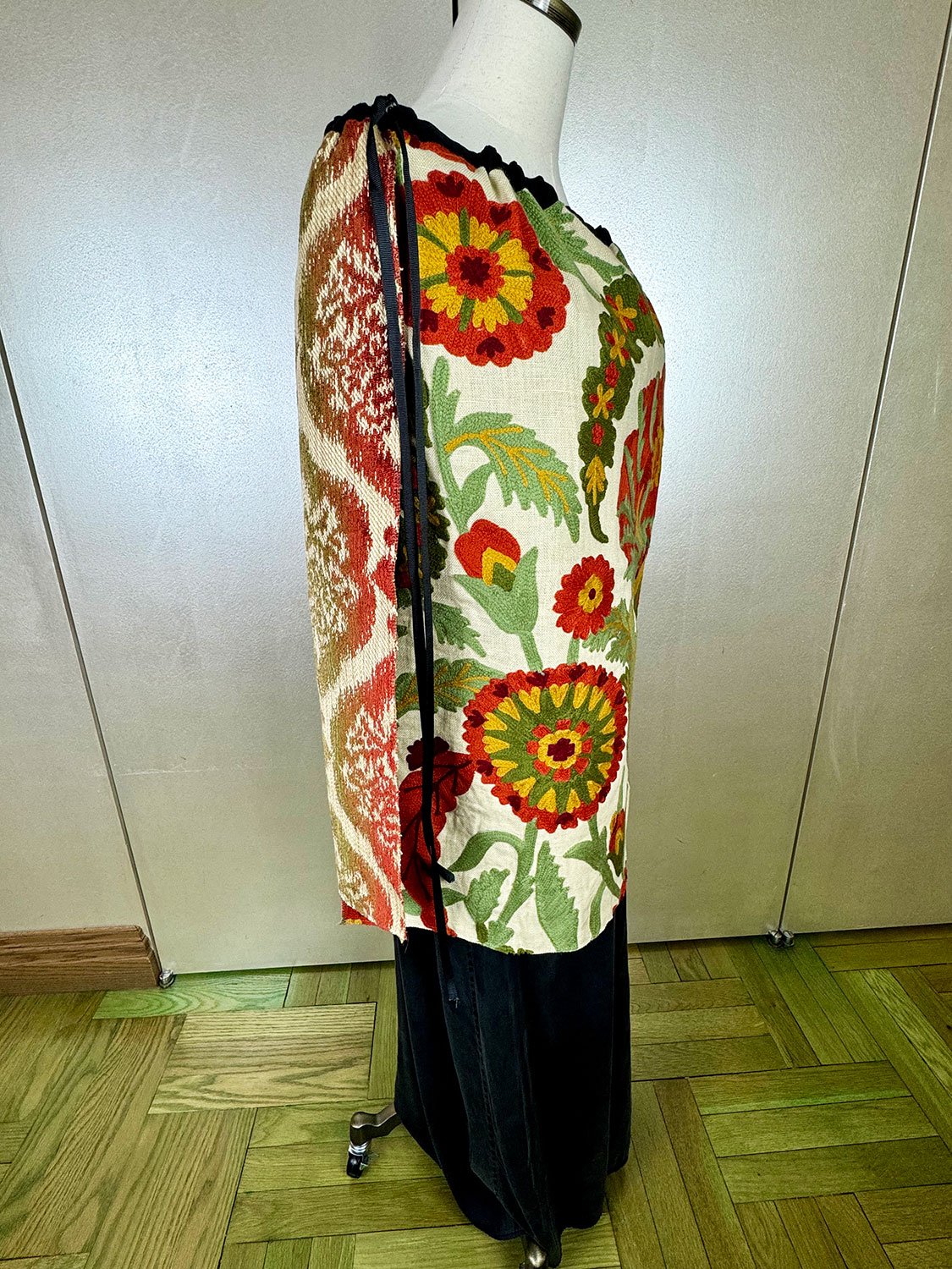 Piper overskirt on mannequin shown as cape side view with long ribbon accents