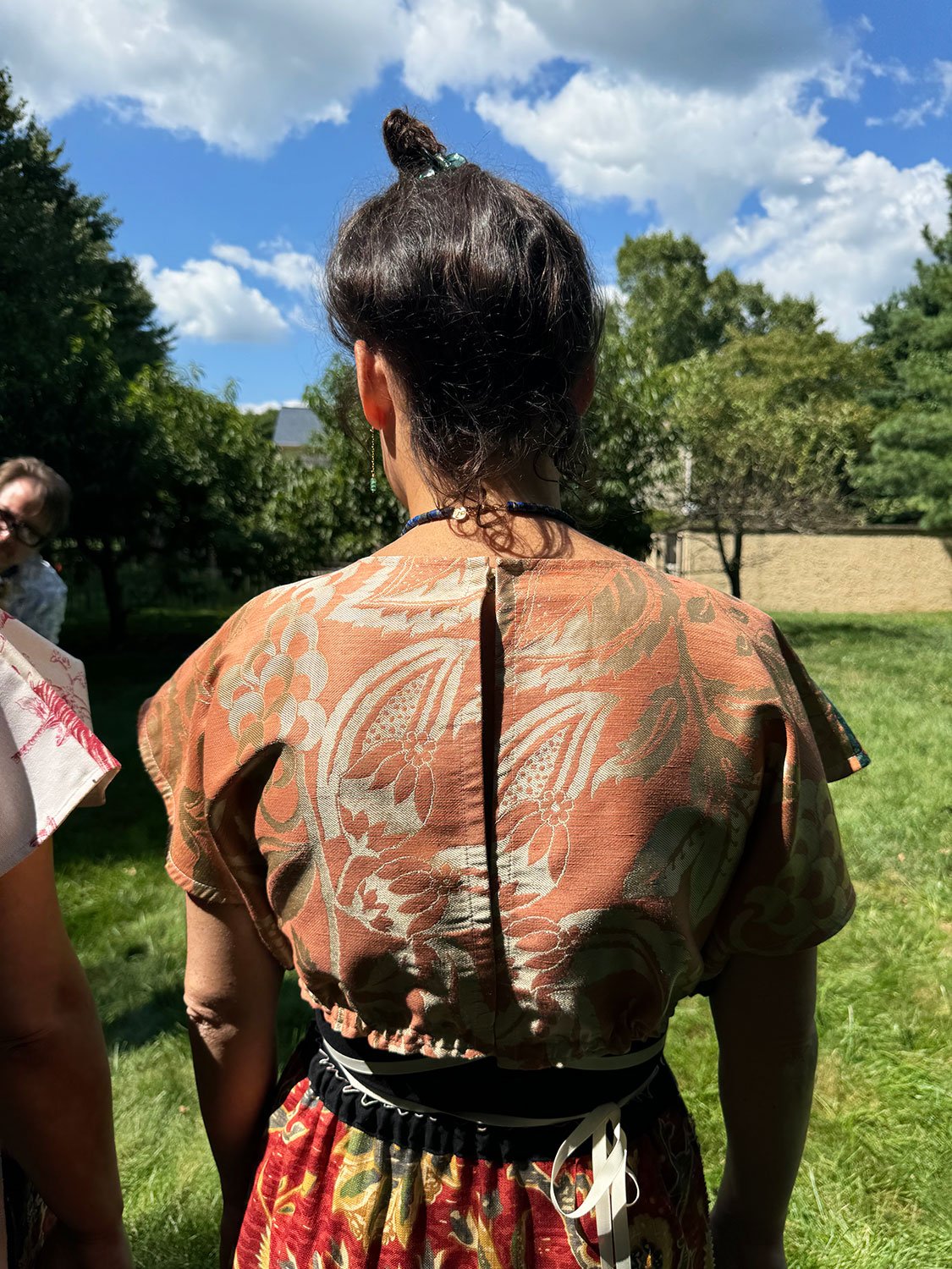 Frida Capelet shown on model back view with Piper Overskirt