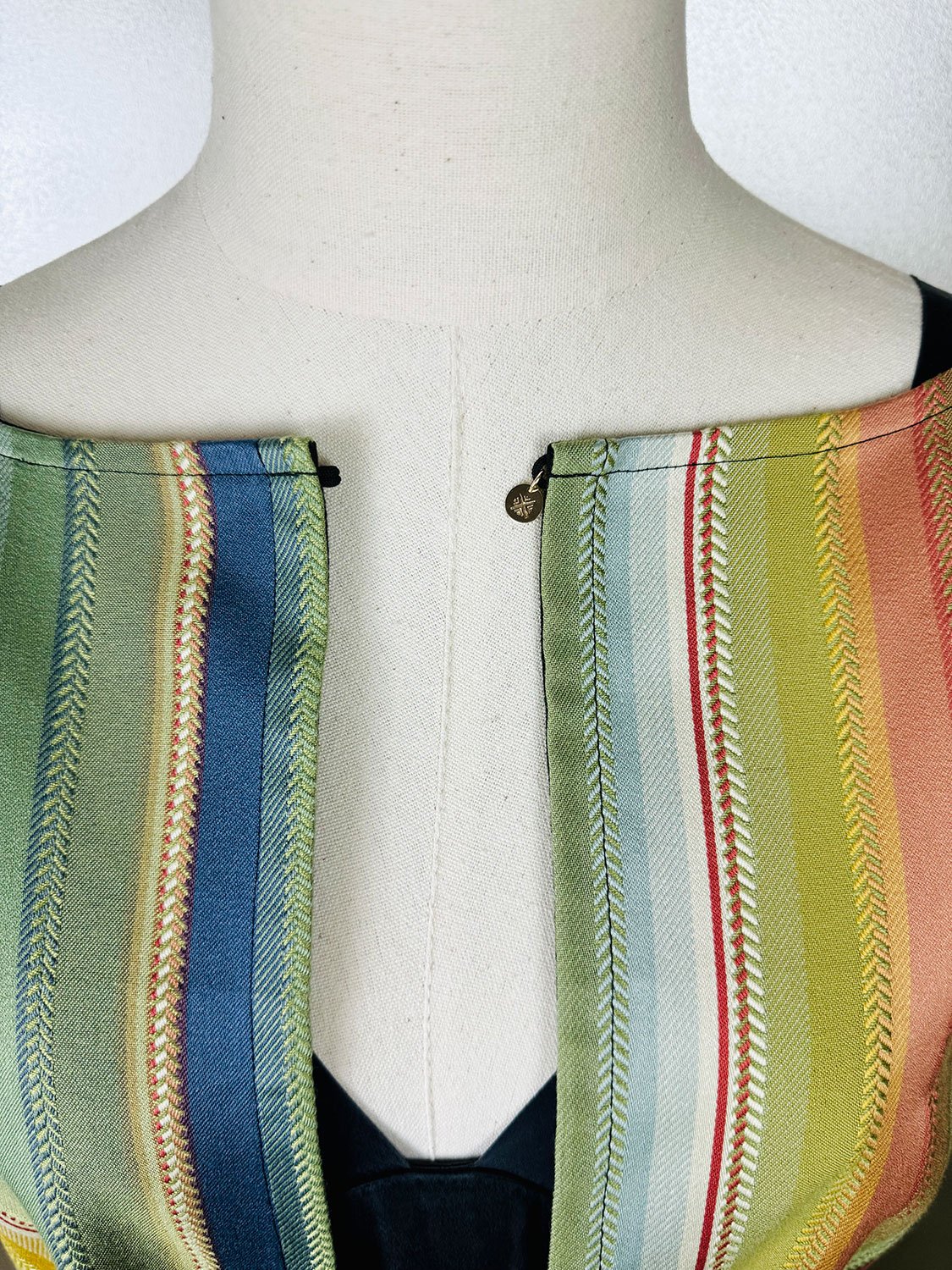 Frida Capelet worn reversed and open on mannequin detail with 14K Gold tag