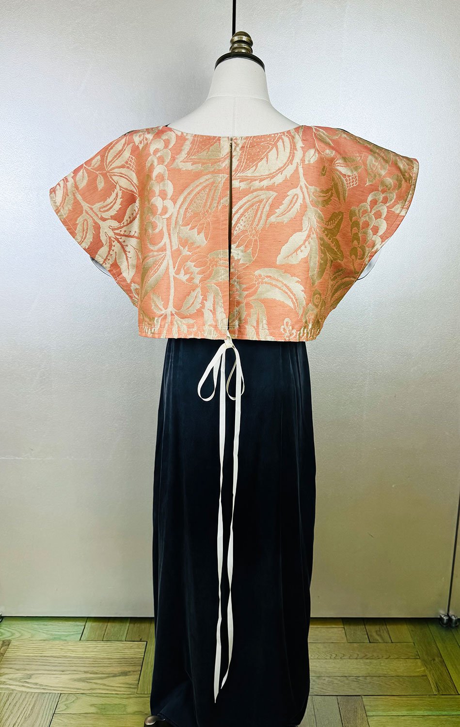 Frida Capelet shown reversed and worn on back closed on mannequin full image with long bow