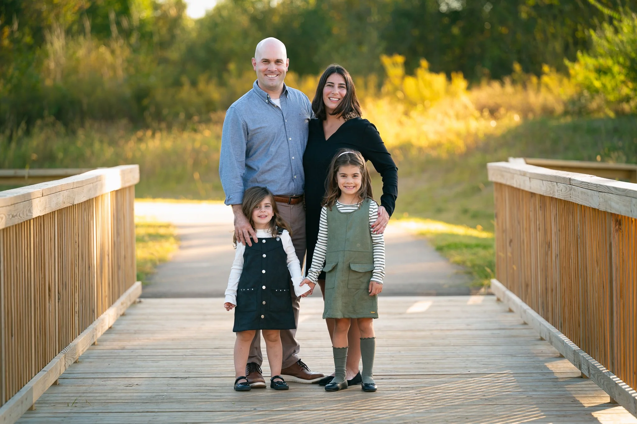 Family of four standing on a wooden boardwalk at golden hour at Carpenter Nature Preserve in Zionsville, Indiana
