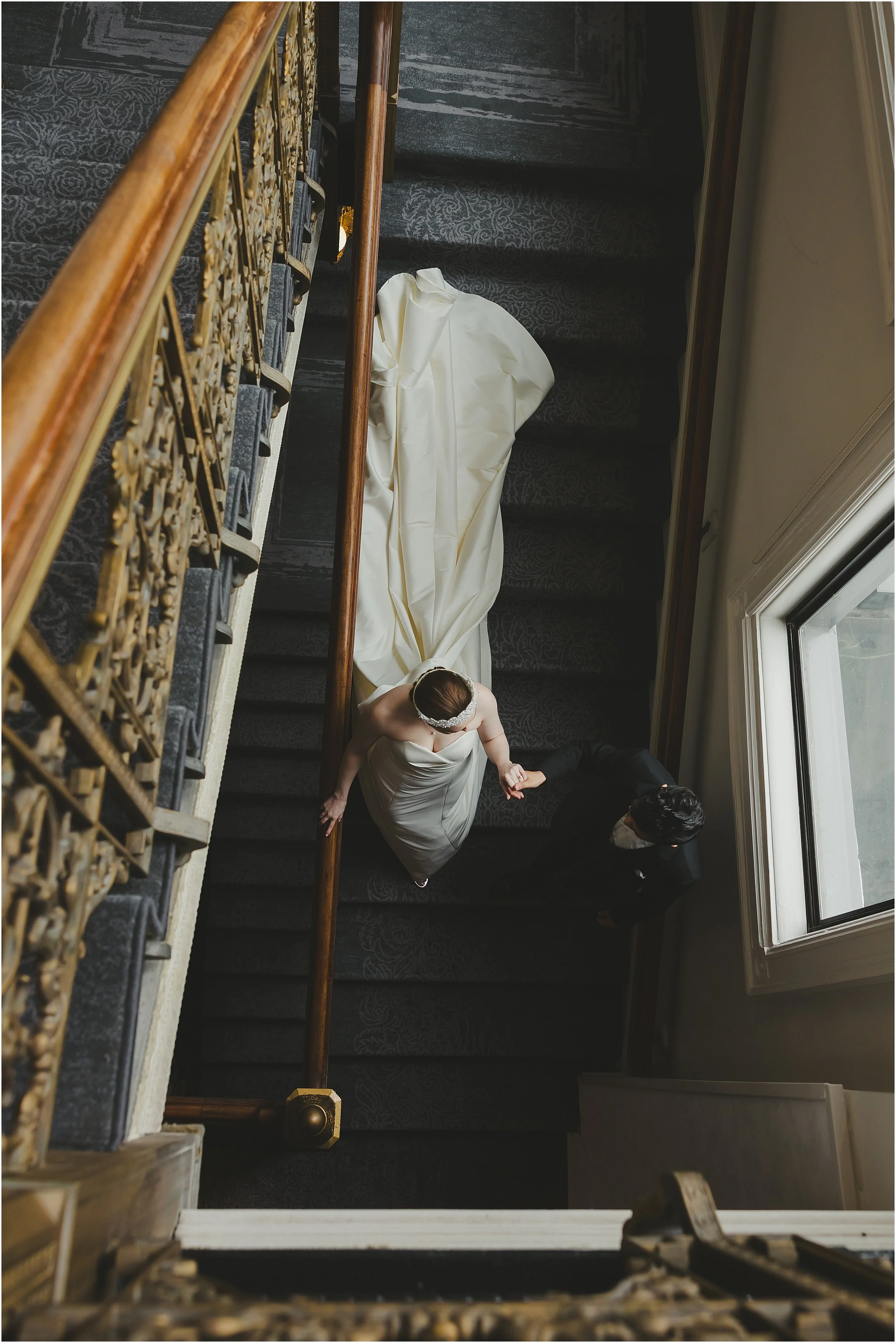 groom-leading-bride-down-stairs-from-above-Pfiste