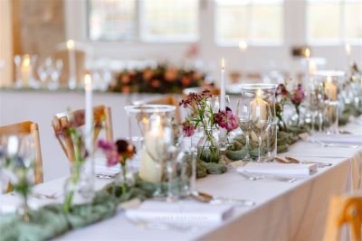 wedding reception table with sage green runner, glassware and candlelight