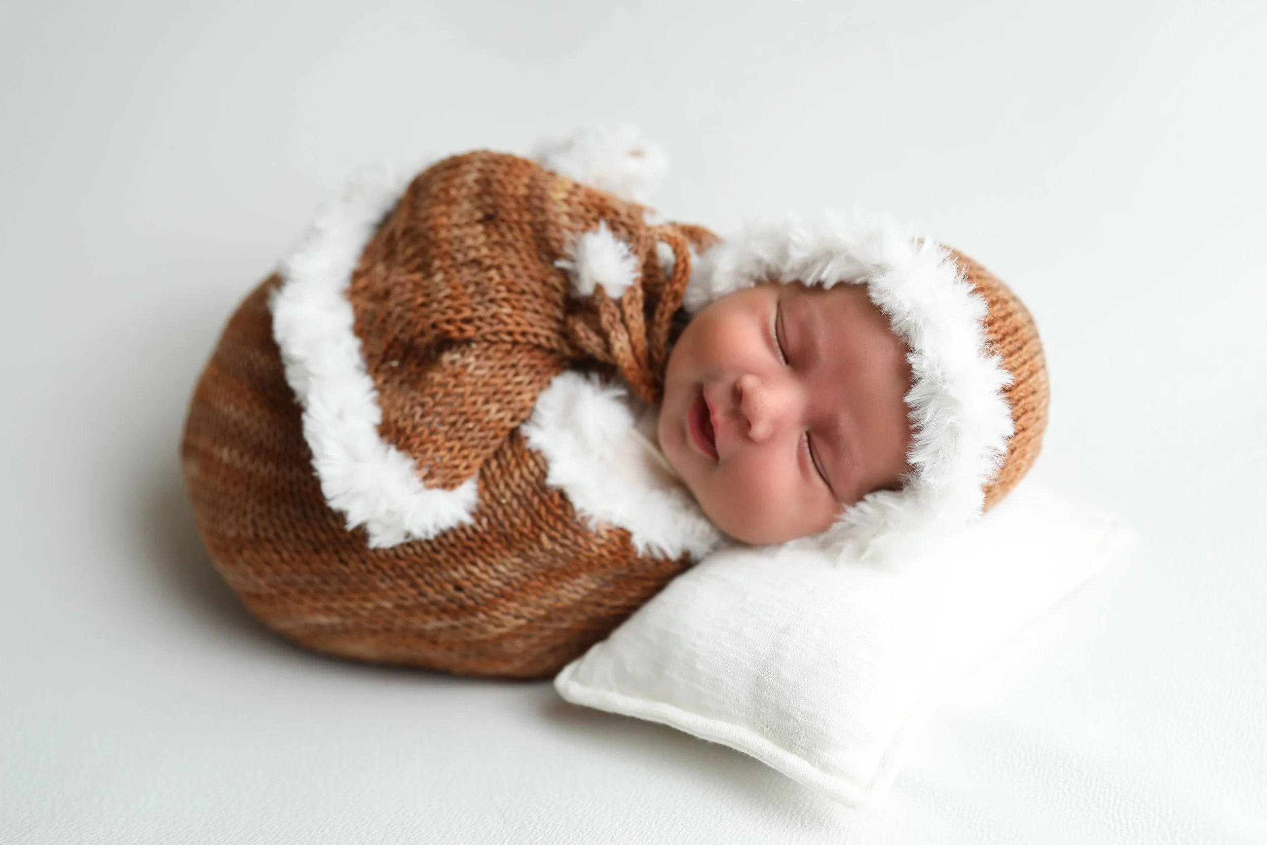 Sleeping newborn posed safely on a white blanket during a professional newborn session