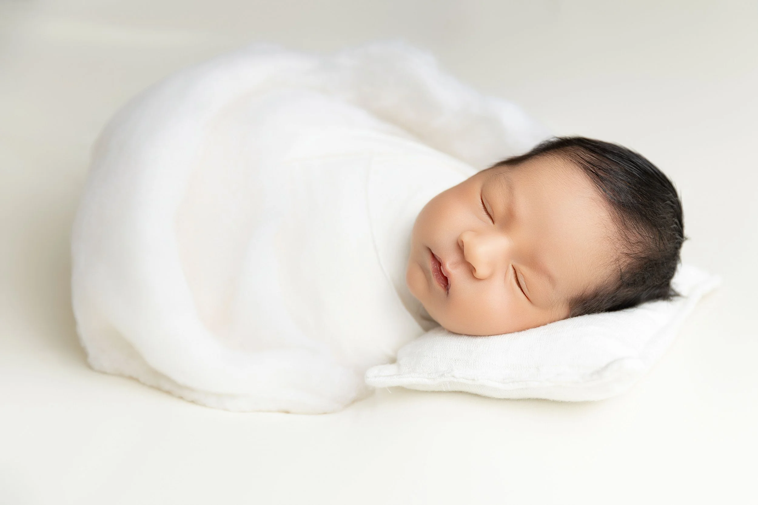 Sleeping newborn wrapped in white during a Palm Desert newborn photography session