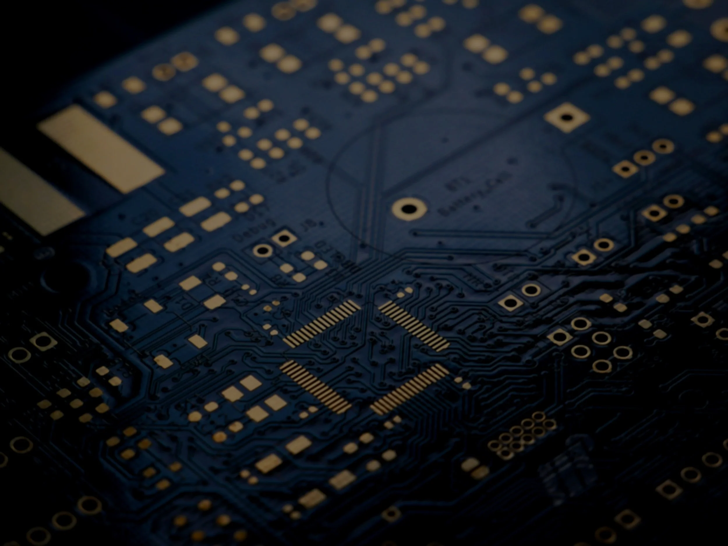 Close-up of a blue printed circuit board with gold contact points and electronic components.