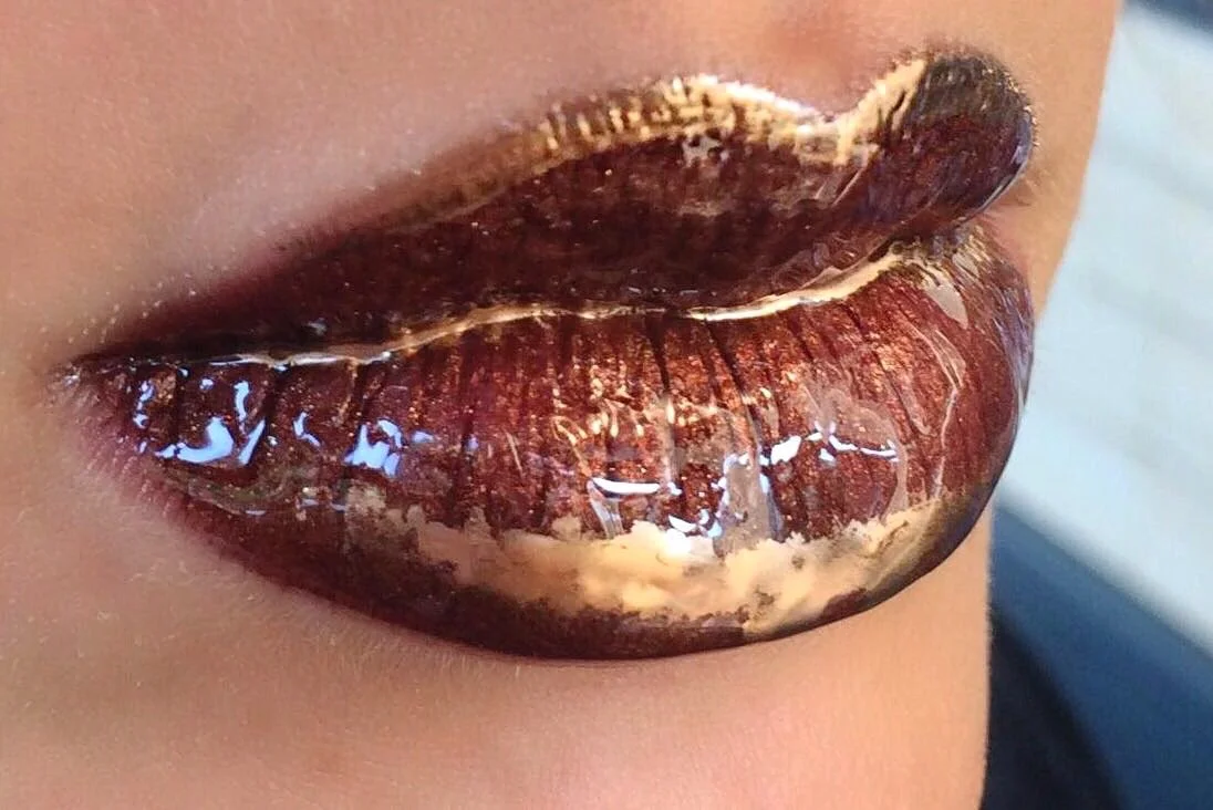 Nahaufnahme von Lippen mit dunklem, glänzendem Make-up in Brauntönen.