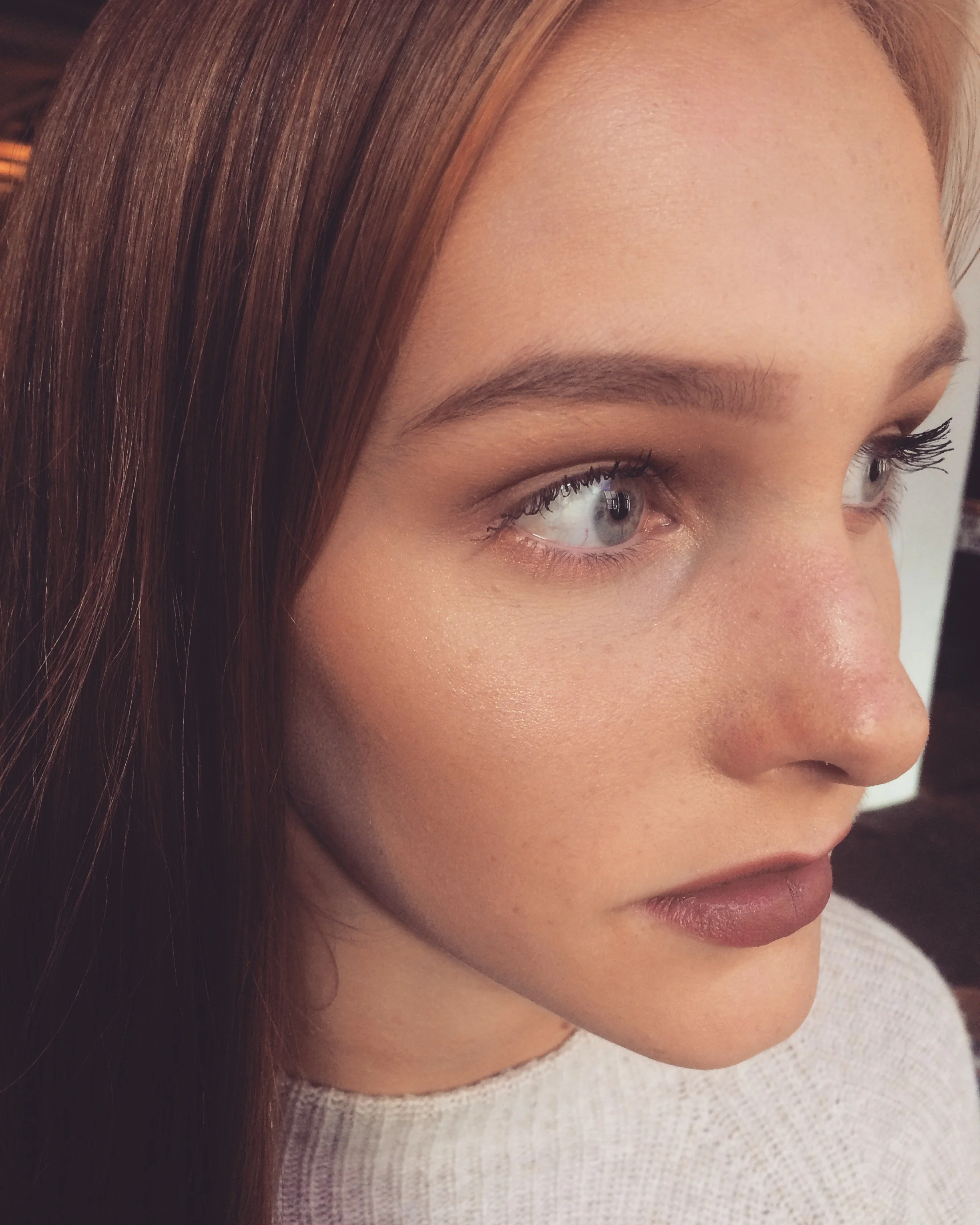 Nahaufnahme eines jungen Mädchens mit roten Haaren, blauer Augenfarbe und natürlichem Makeup.