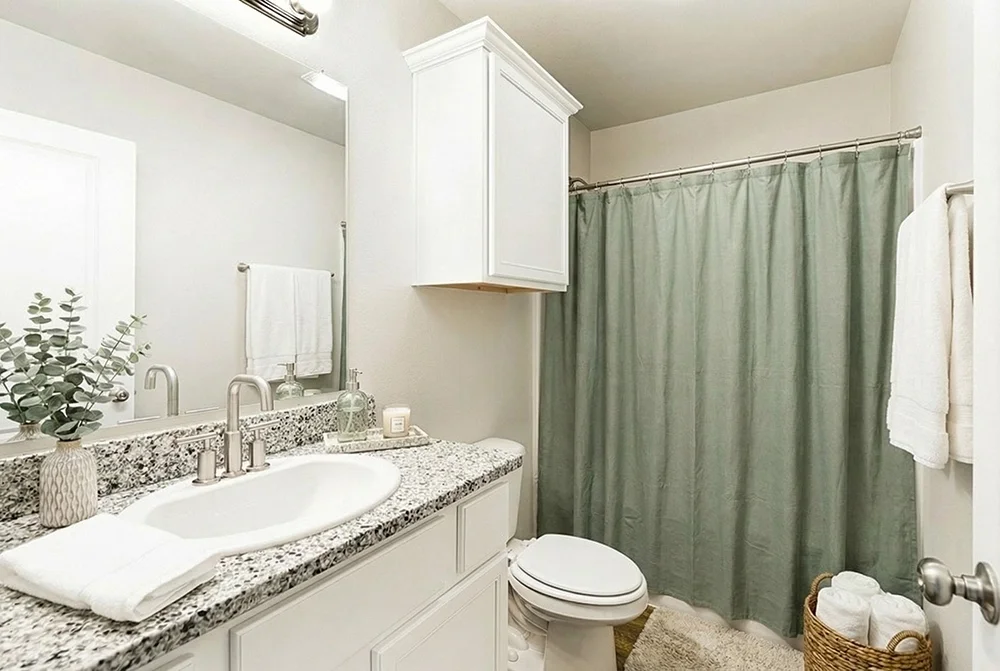 Bathroom with a granite countertop sink, white cabinetry, a green shower curtain, and white towels.