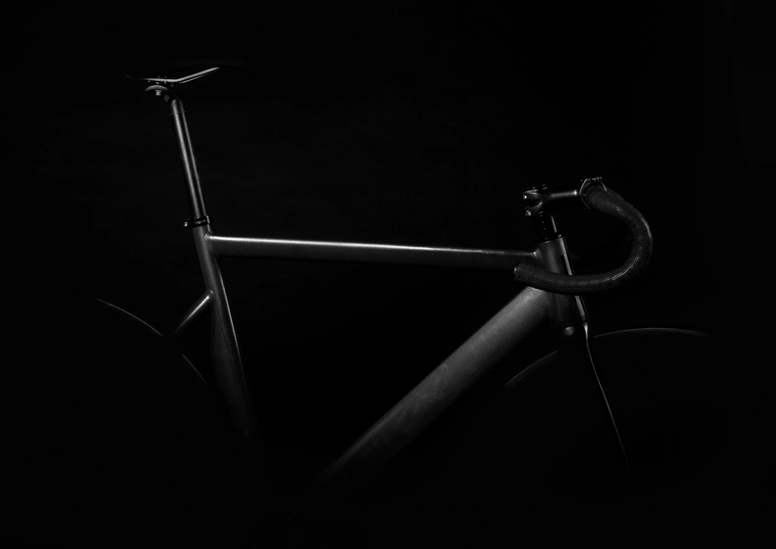 A close-up of a modern bicycle's handlebar and partial frame in a dark setting.