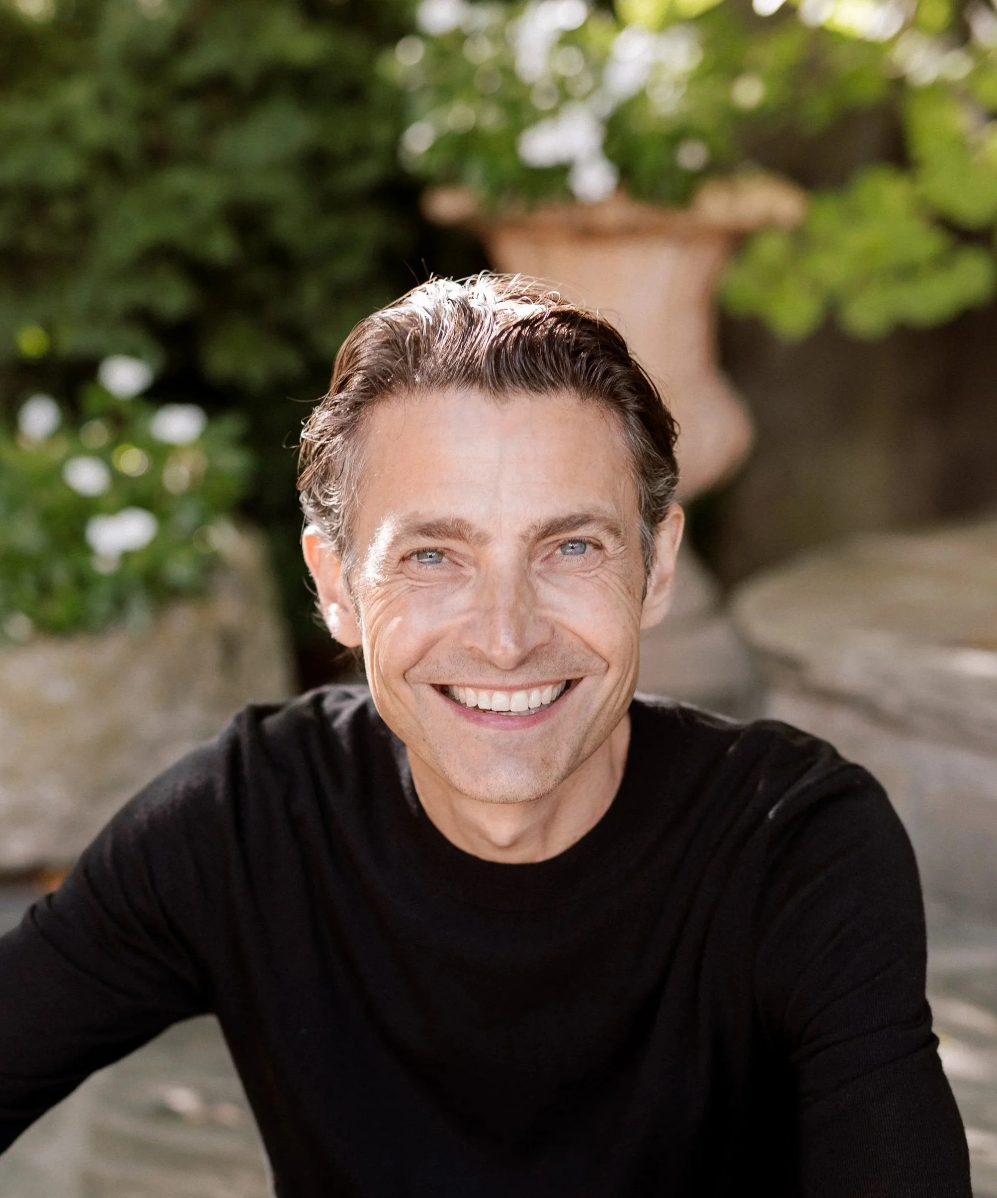 Robe dube wearing a black shirt, outdoors with greenery in the background.