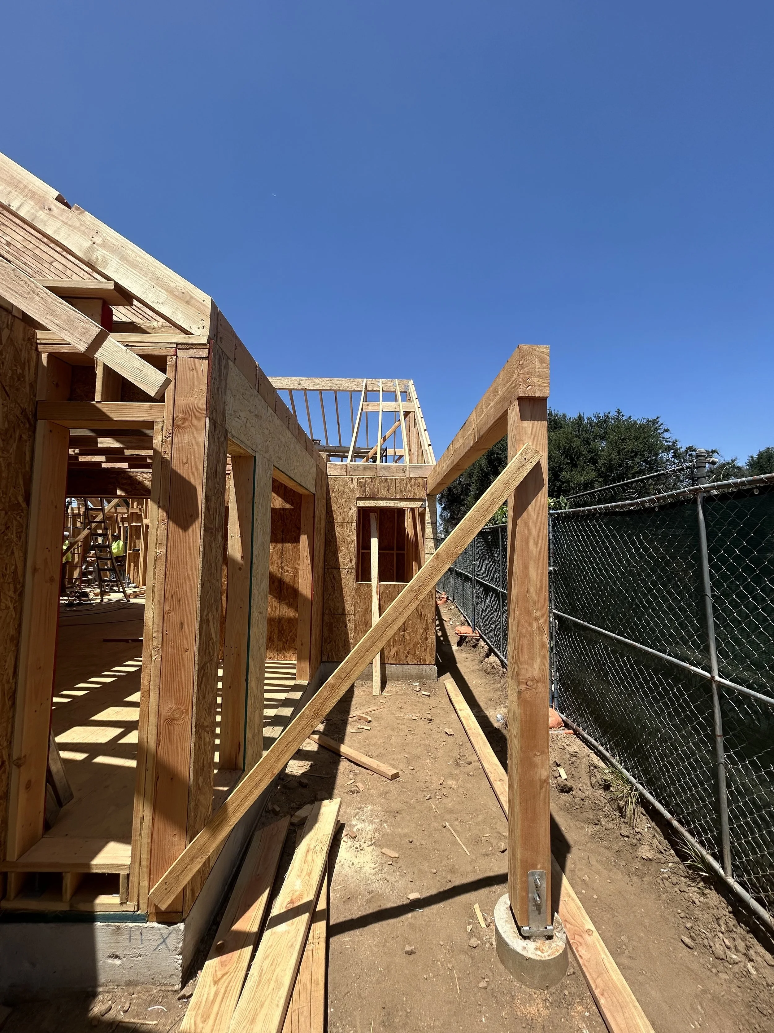 Wooden framing for a building under construction with blue sky in background.